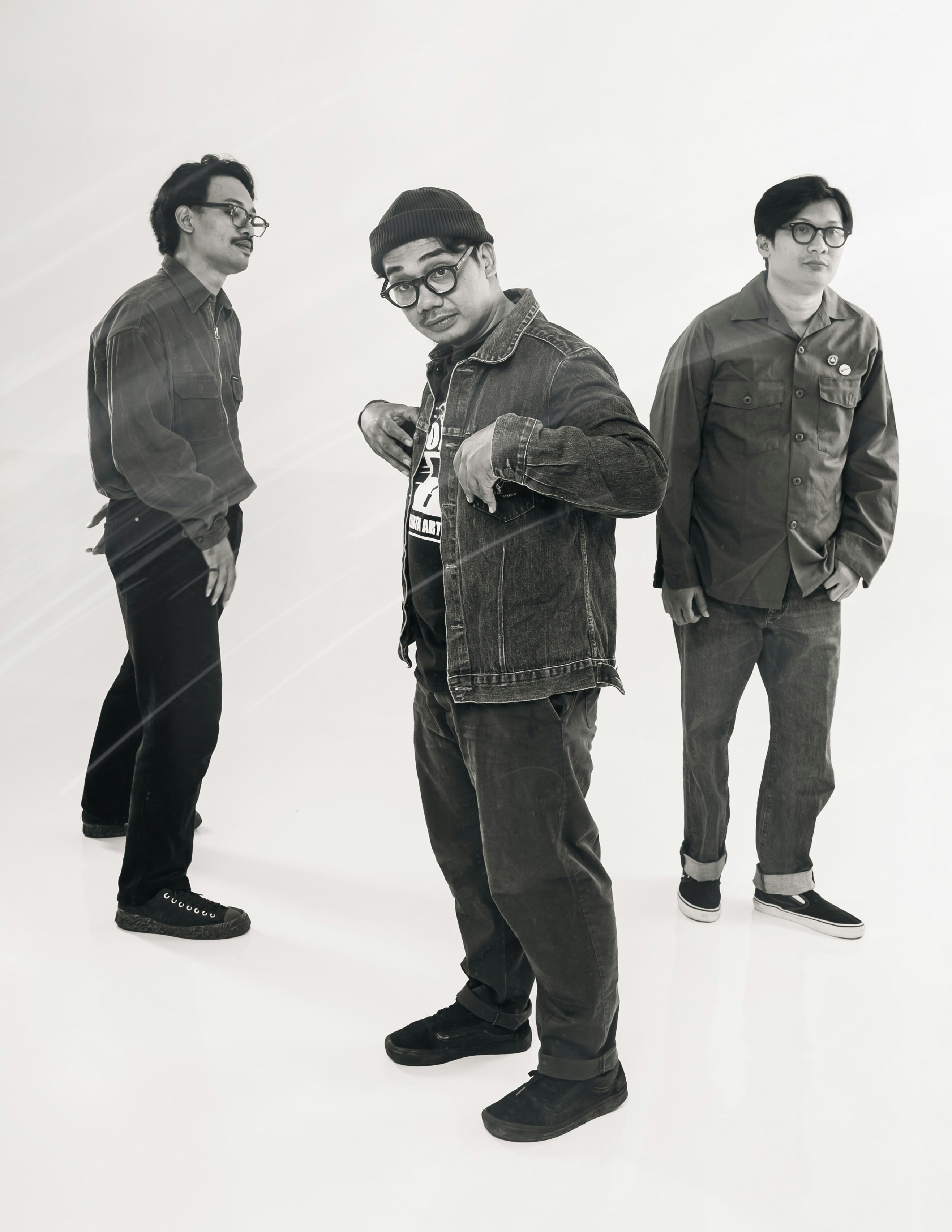 Three casually dressed men posing against a white background.