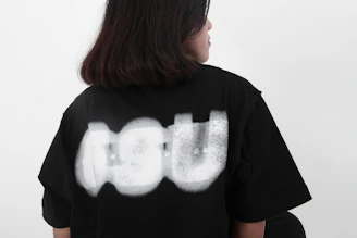 A person wearing a black t-shirt with abstract white design.