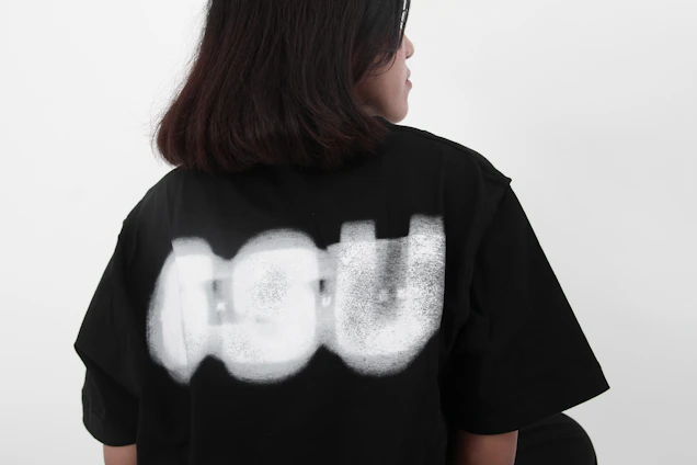 A person wearing a black t-shirt with abstract white design.