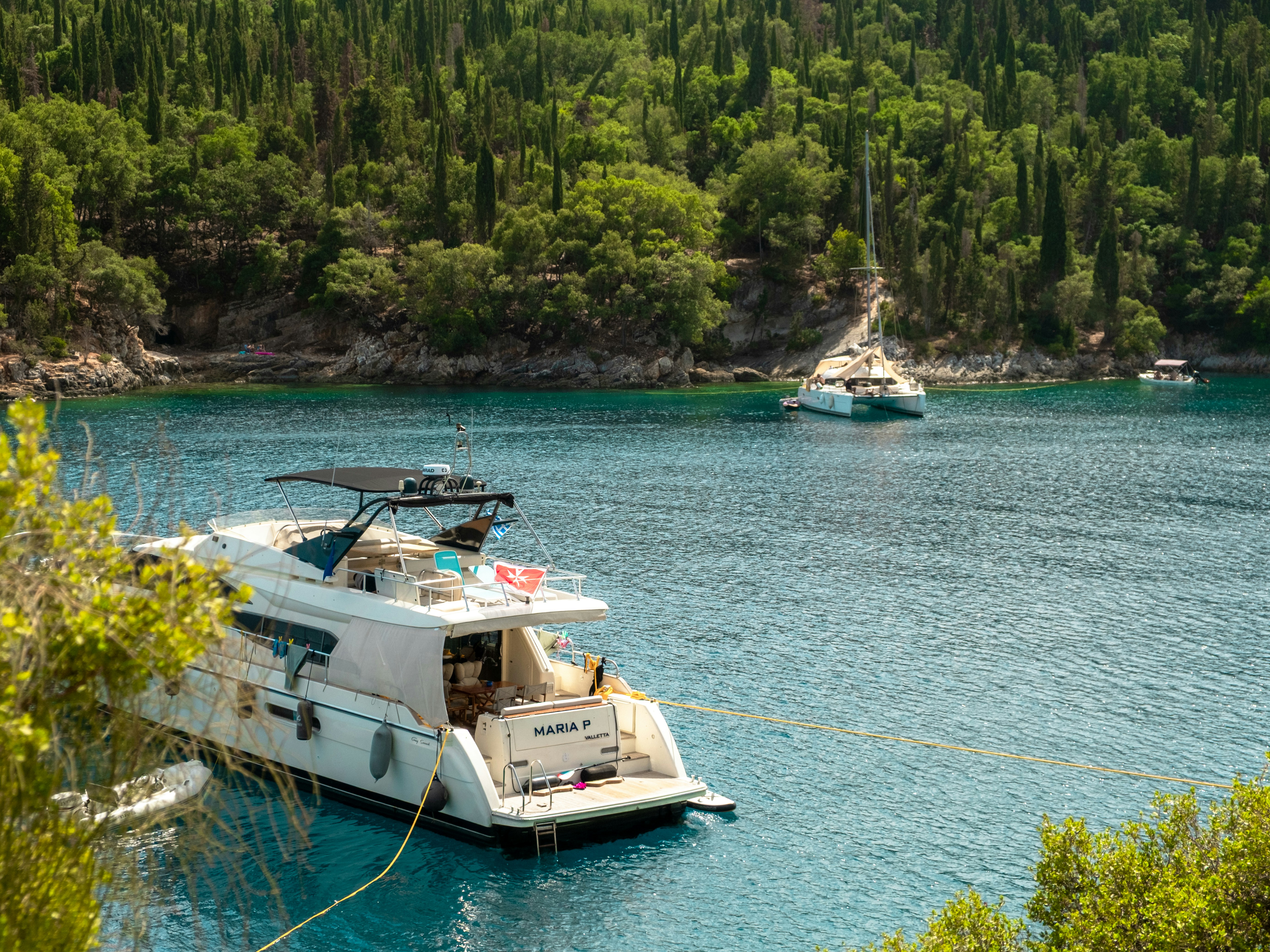 Yacht ormeggiati in una baia tranquilla circondata da una foresta verde.