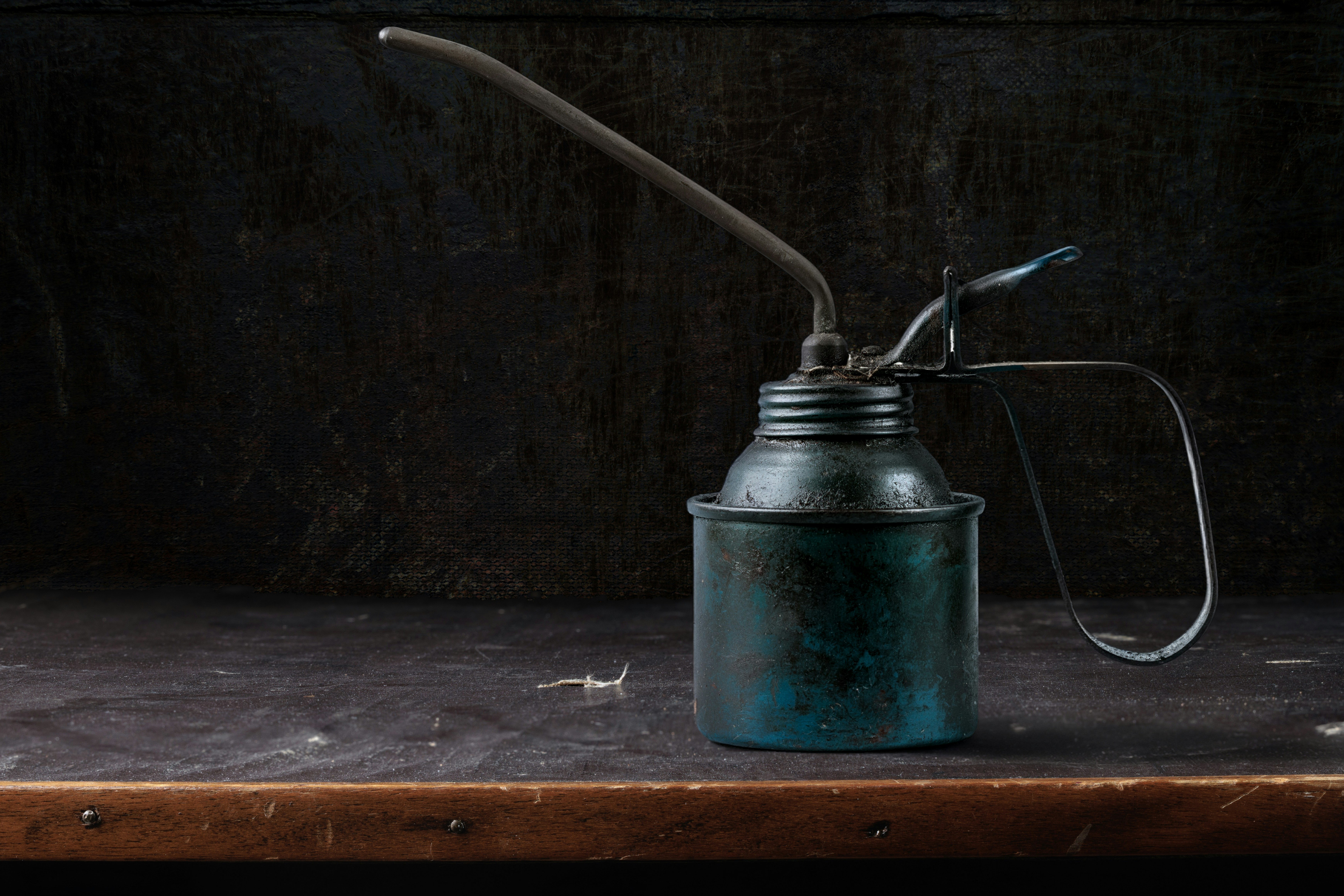 Vintage blue oil can on a rustic wooden surface.