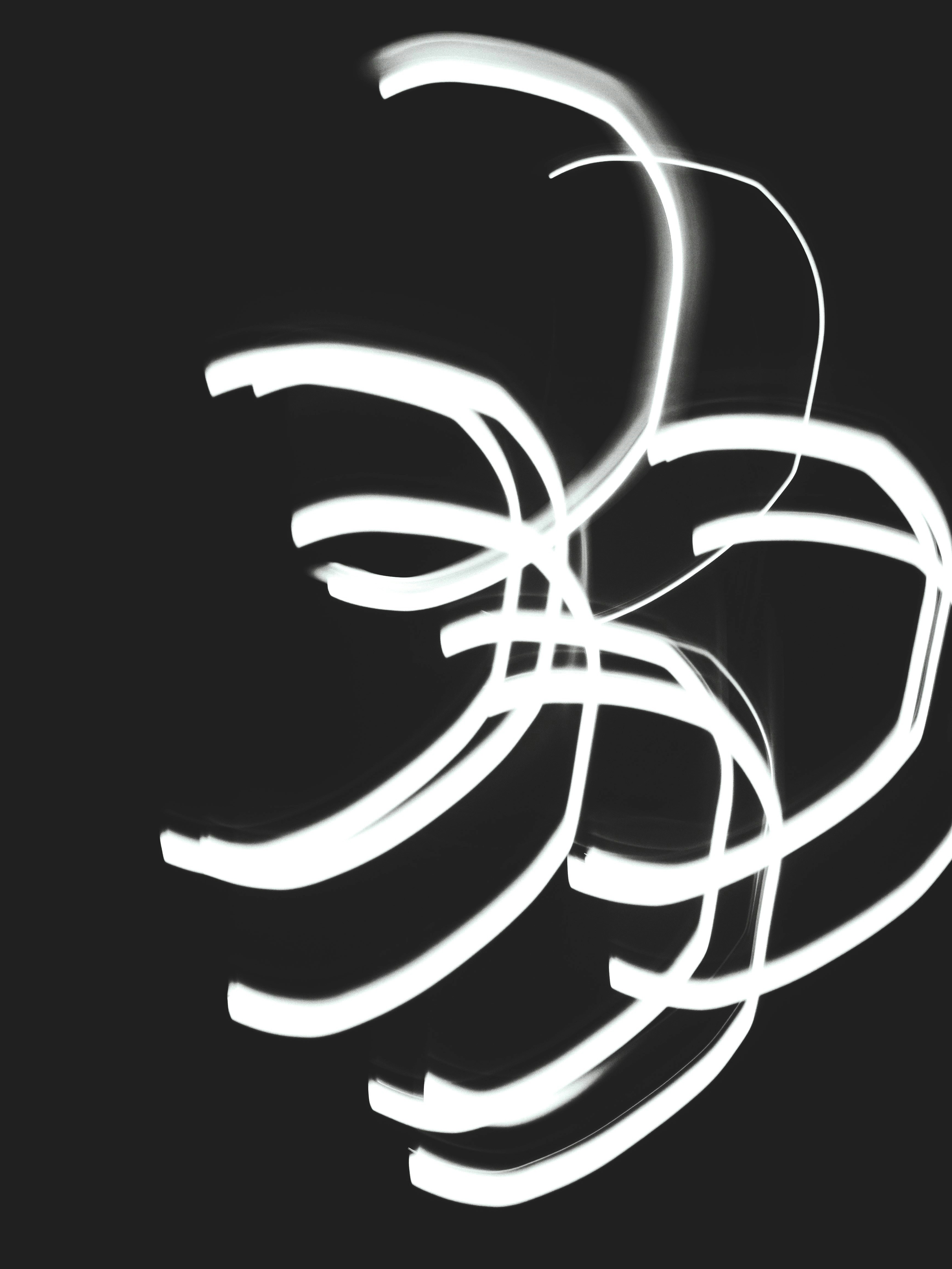 Abstract white light trails swirling on a dark background.