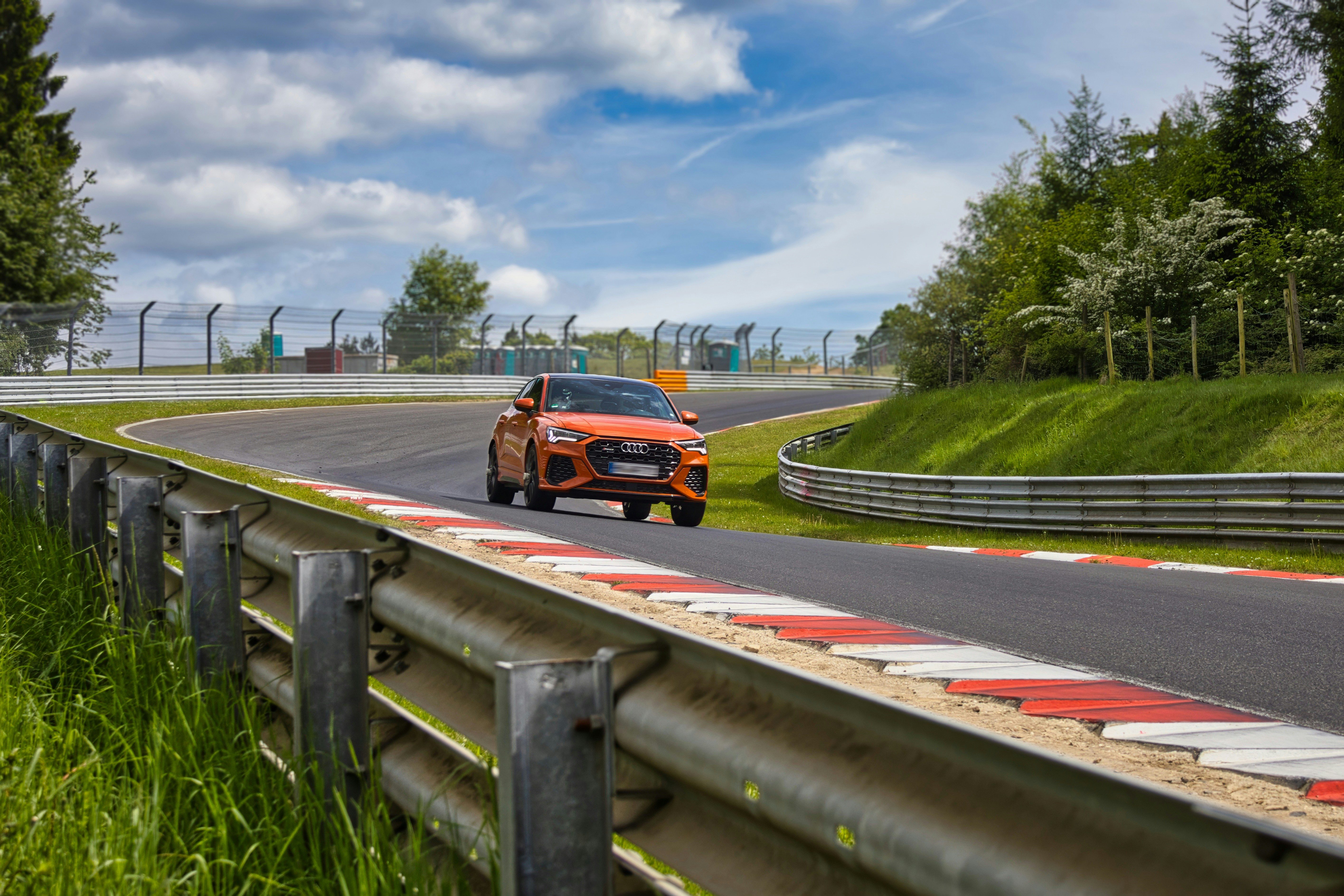 Voiture de sport orange sur une piste sinueuse.