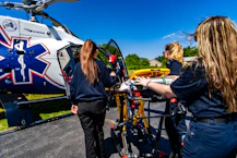 Medical personnel load a stretcher into an air ambulance helicopter.