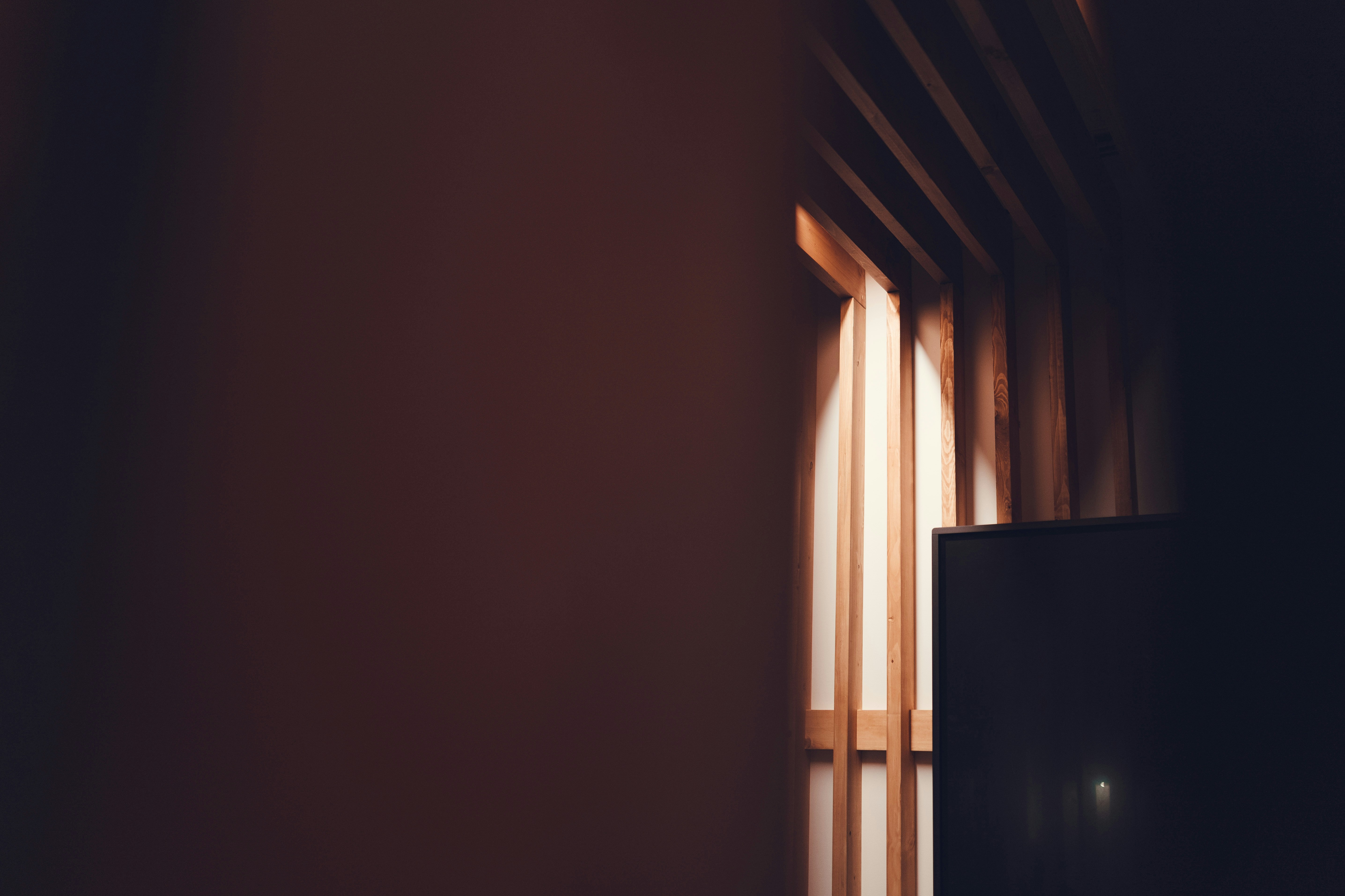 Narrow light beam entering a dark room with wooden slats.