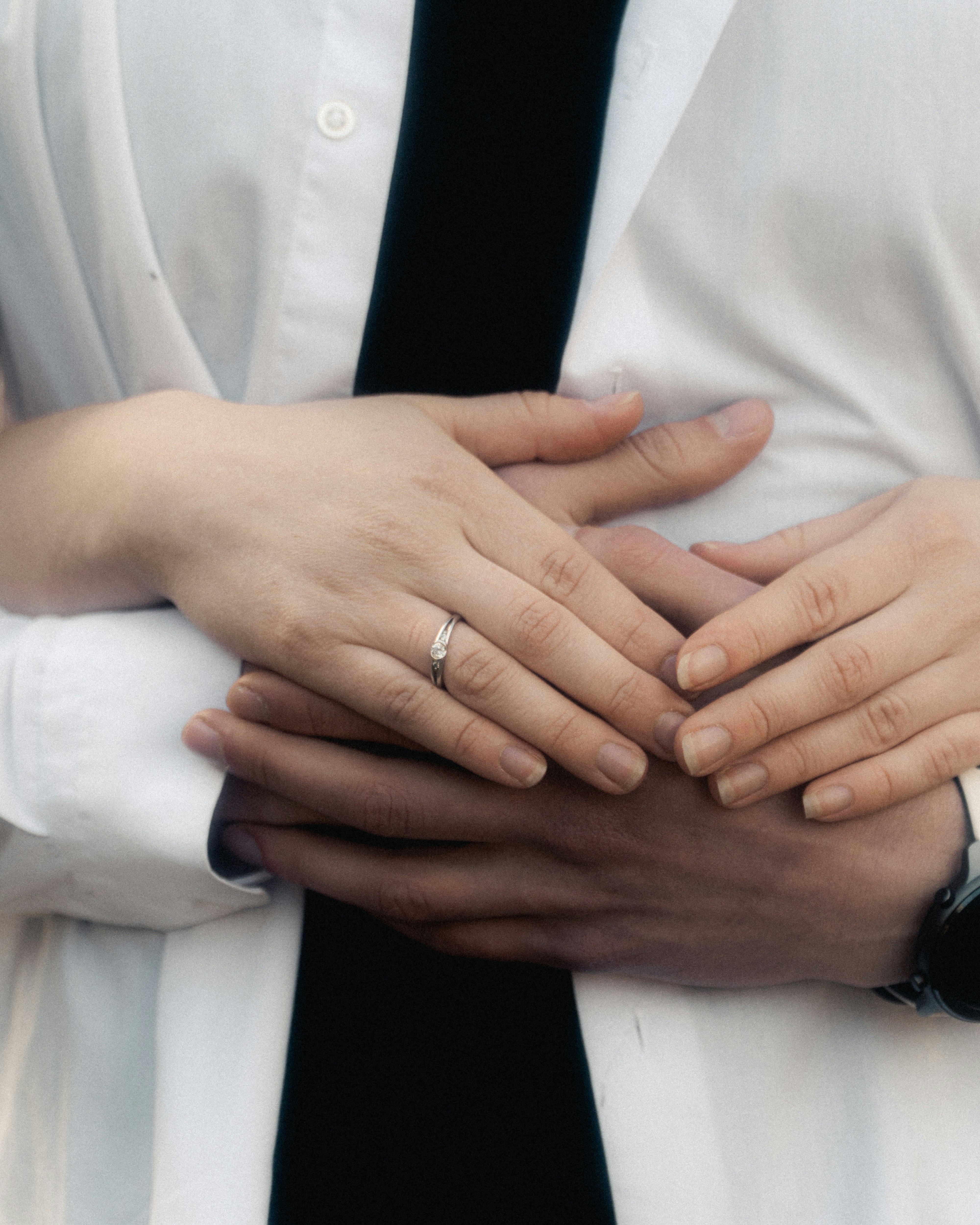 Couple's hands intertwined, one wearing an engagement ring.