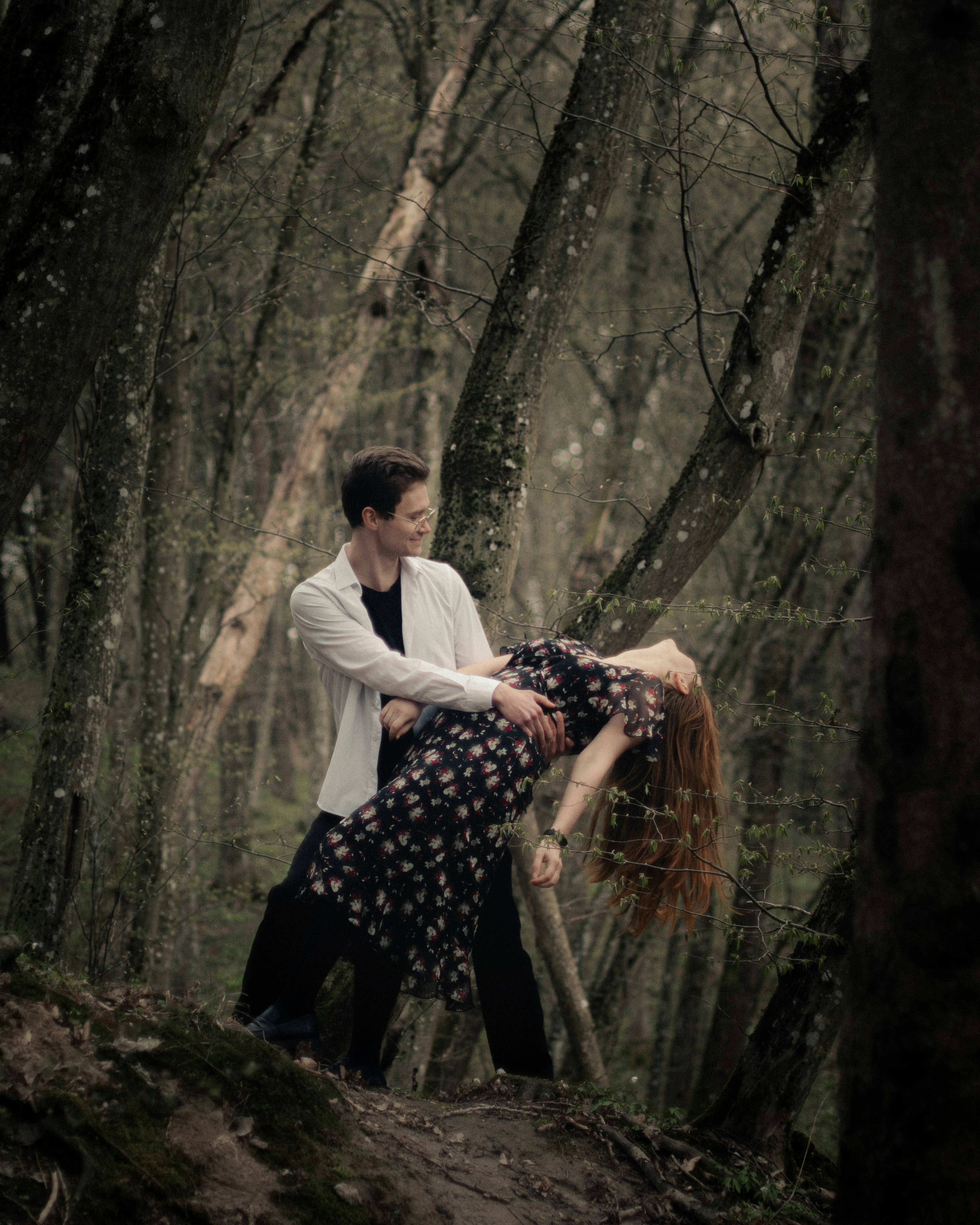 Man and woman dancing in a dark, mysterious forest.