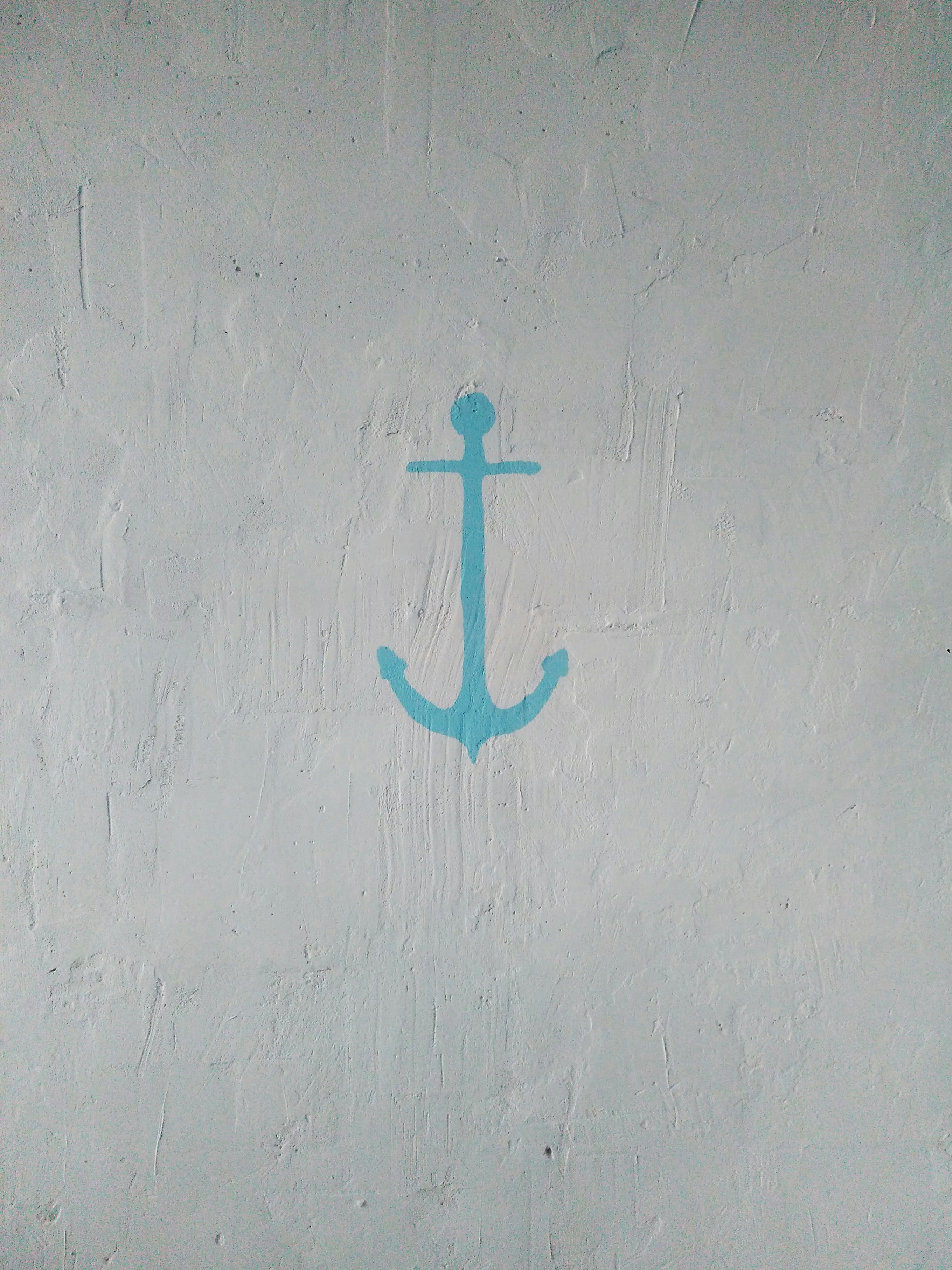 Ein hellblauer Anker, der auf eine strukturierte weiße Wand gemalt ist.