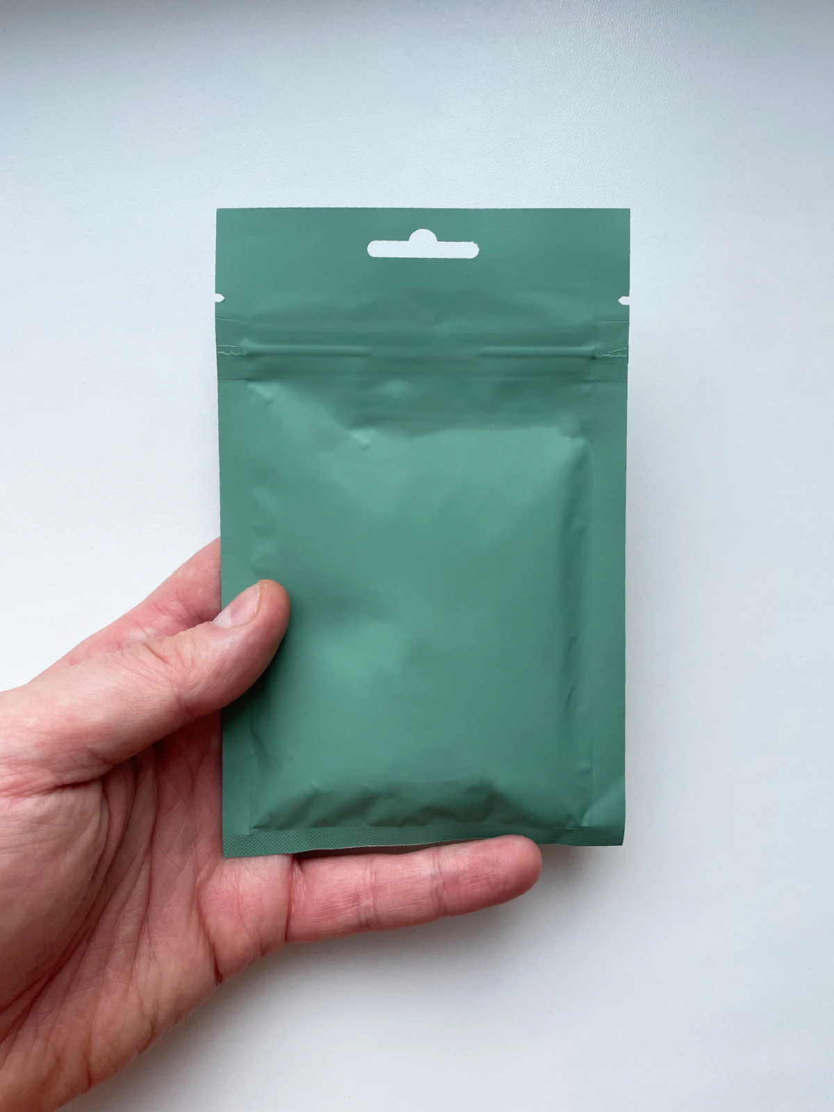 A hand holding a blank stand-up pouch