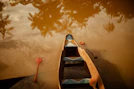 Canoe on muddy water with palm tree reflections