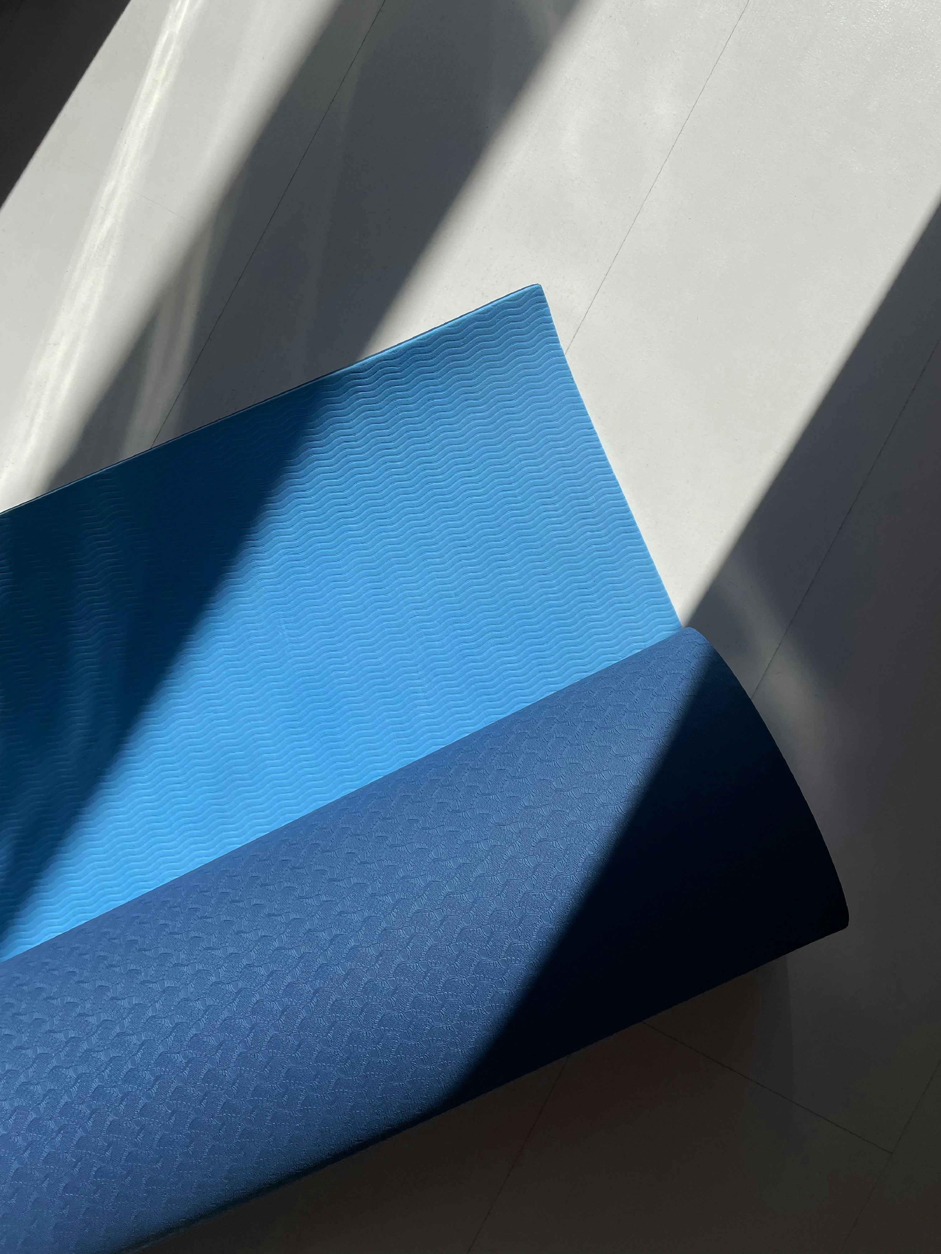 Close-up of a blue textured yoga mat surface in sunlight