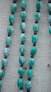 Mottled turquoise beads strung with small black beads.