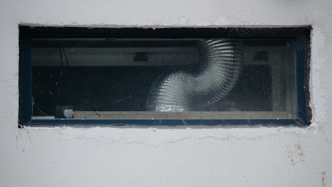 Flexible air duct run visible through a small access opening