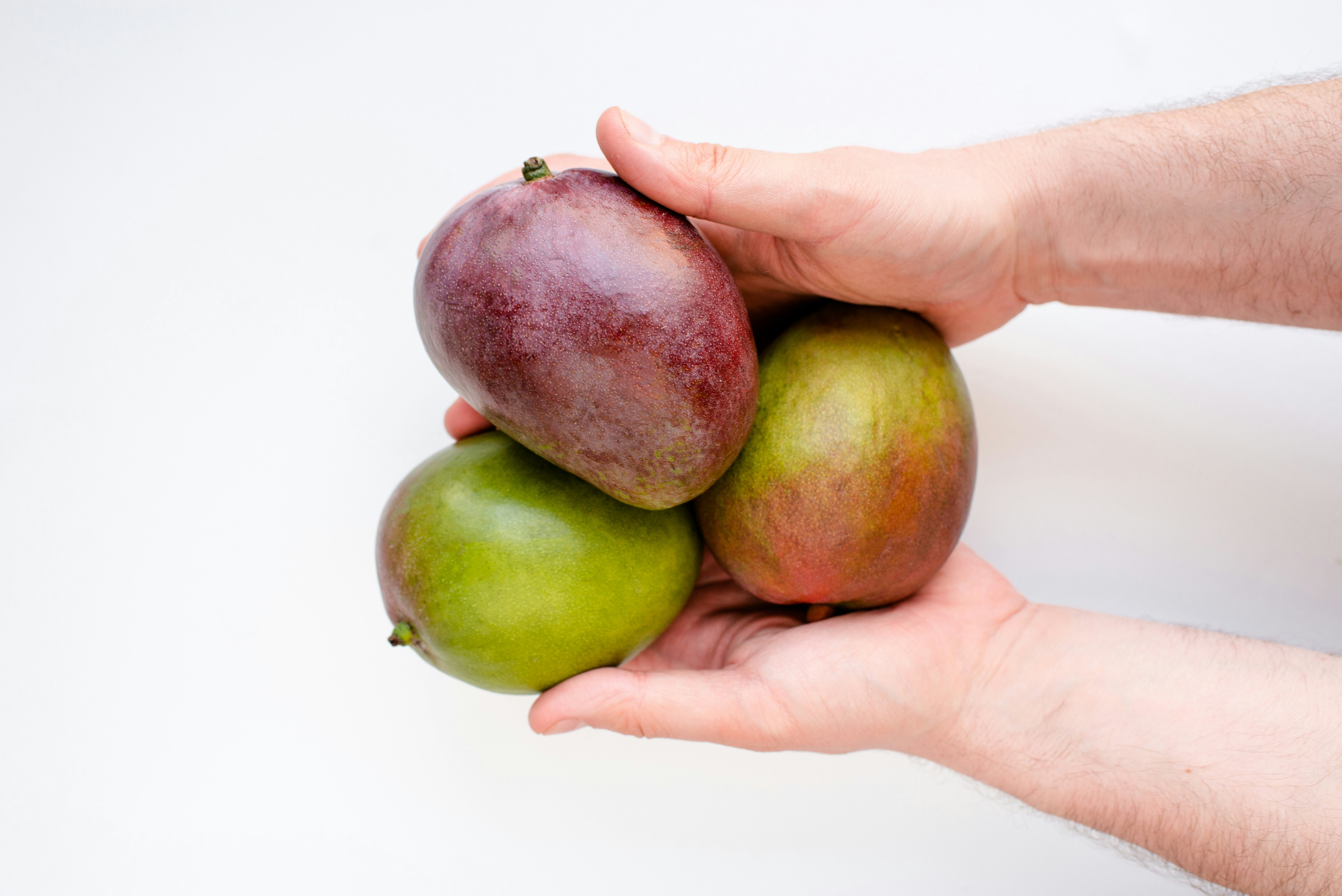 Dos manos sosteniendo tres mangos sobre un fondo blanco.