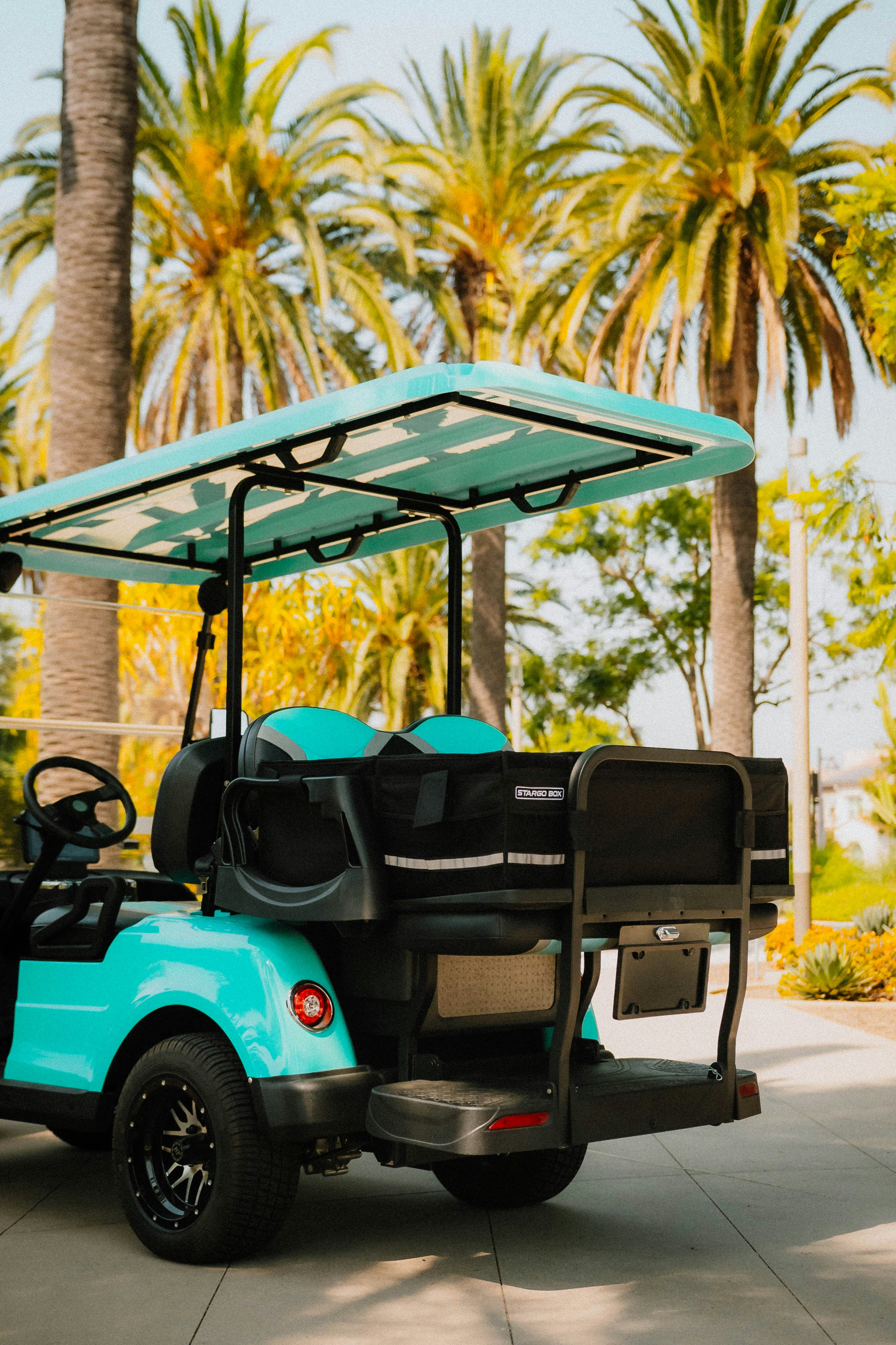A turquoise golf cart parked outdoors with palm trees