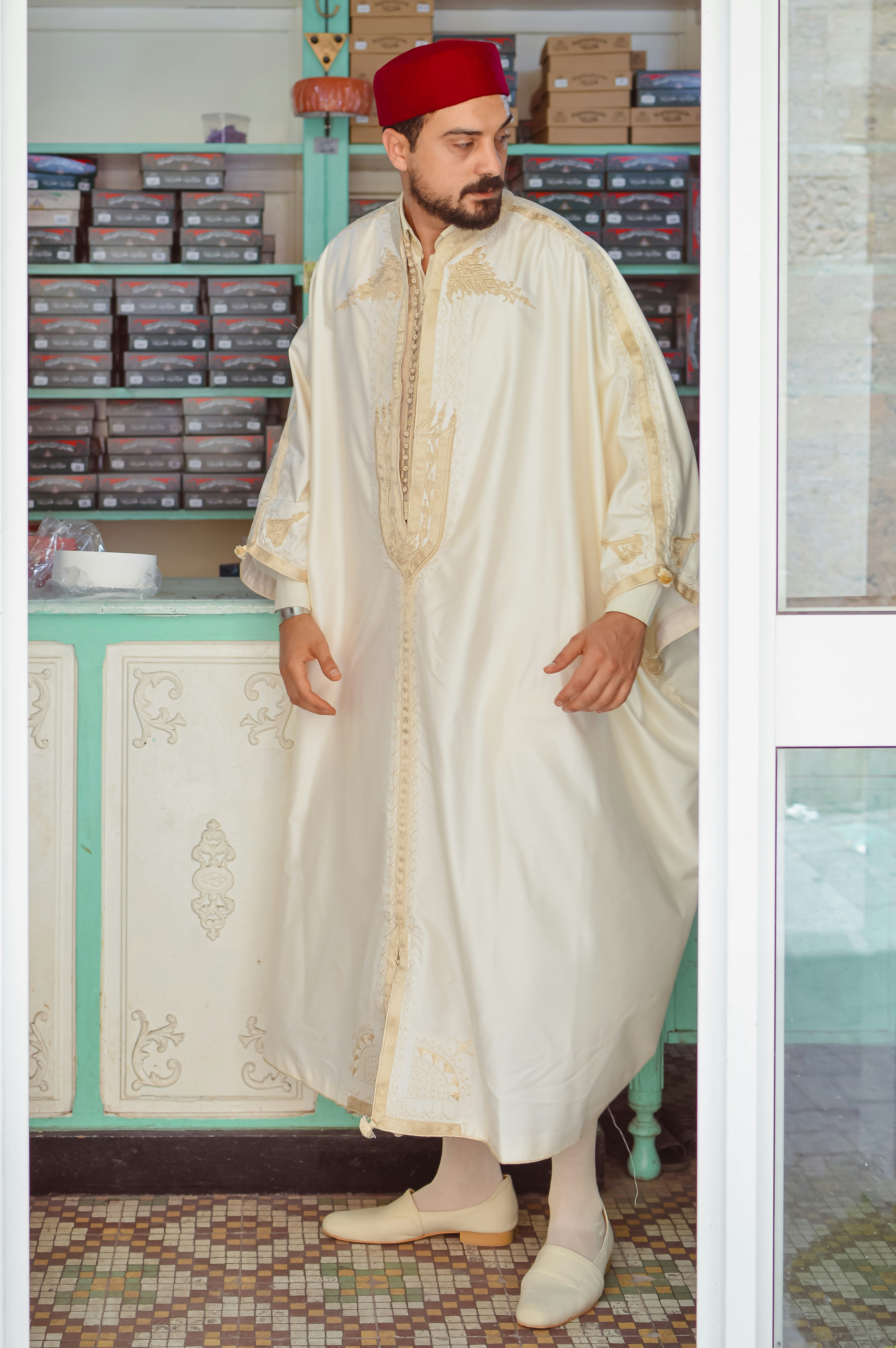A man in traditional moroccan attire stands in a shop.