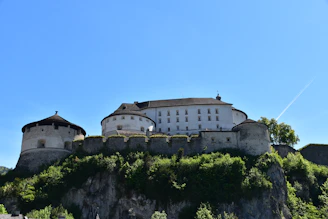 Majestic castle atop a green hill under clear blue sky.