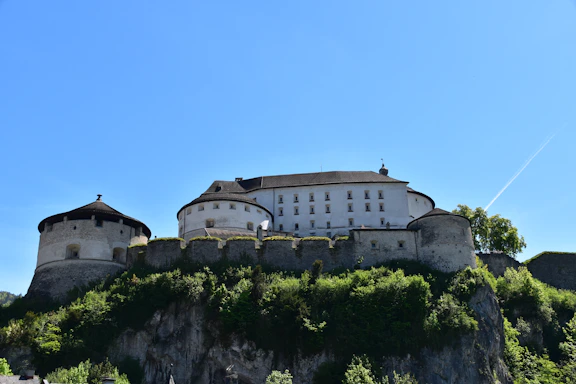 Majestic castle atop a green hill under clear blue sky.