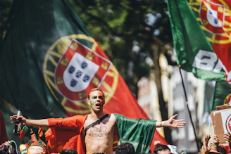 Enthusiastic man with portuguese flag cape and outstretched arms.