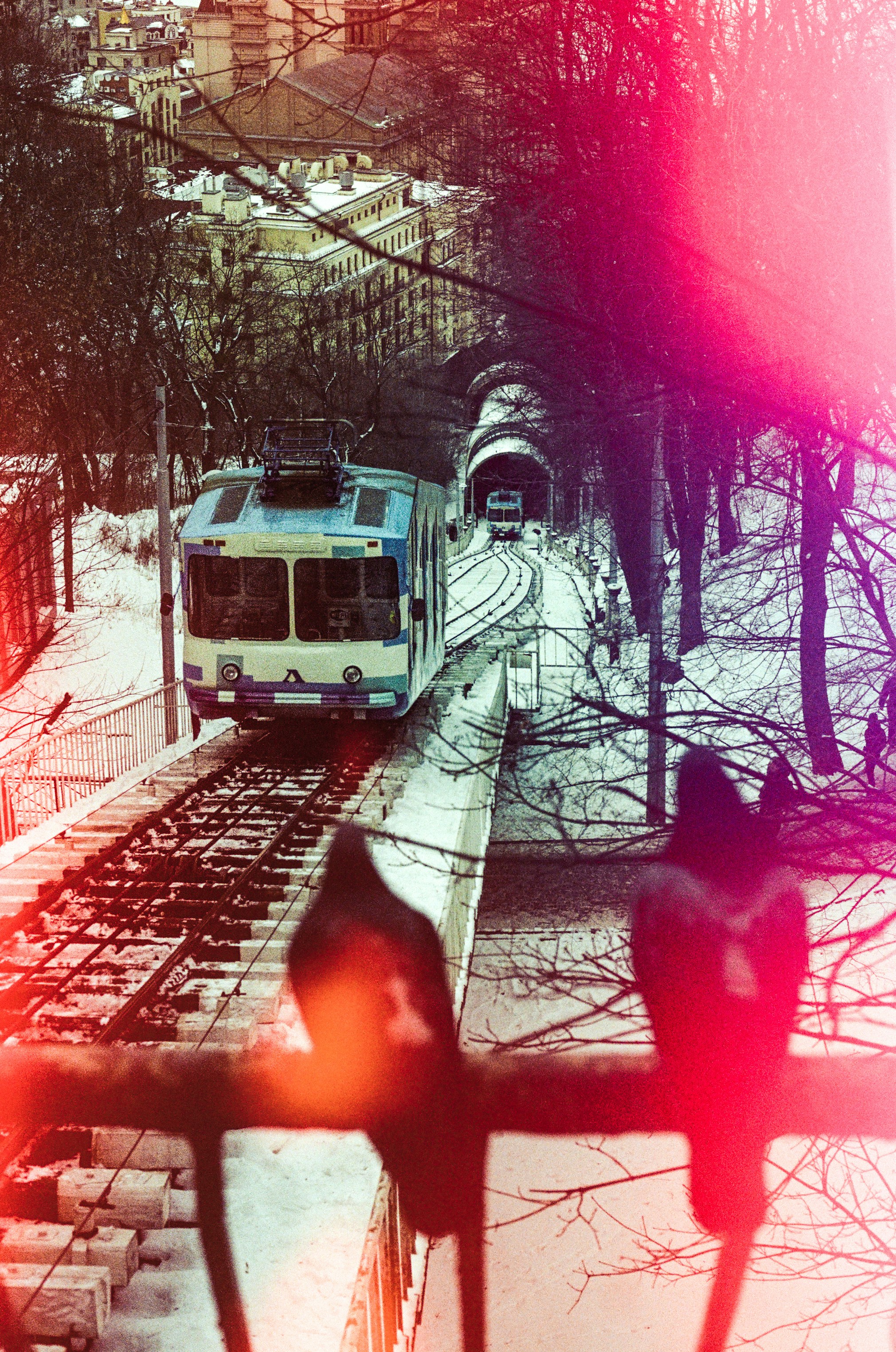 Funicular train on snowy tracks in a winter urban landscape.