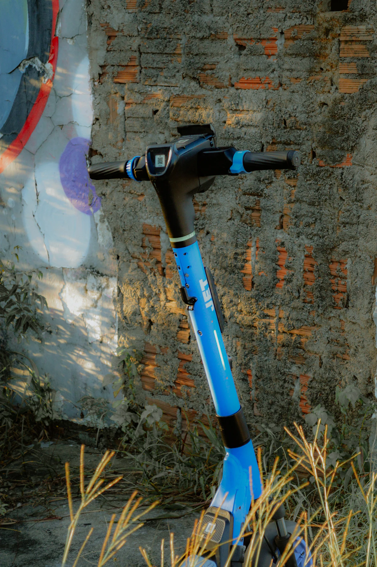 Blue electric scooter against a brick wall