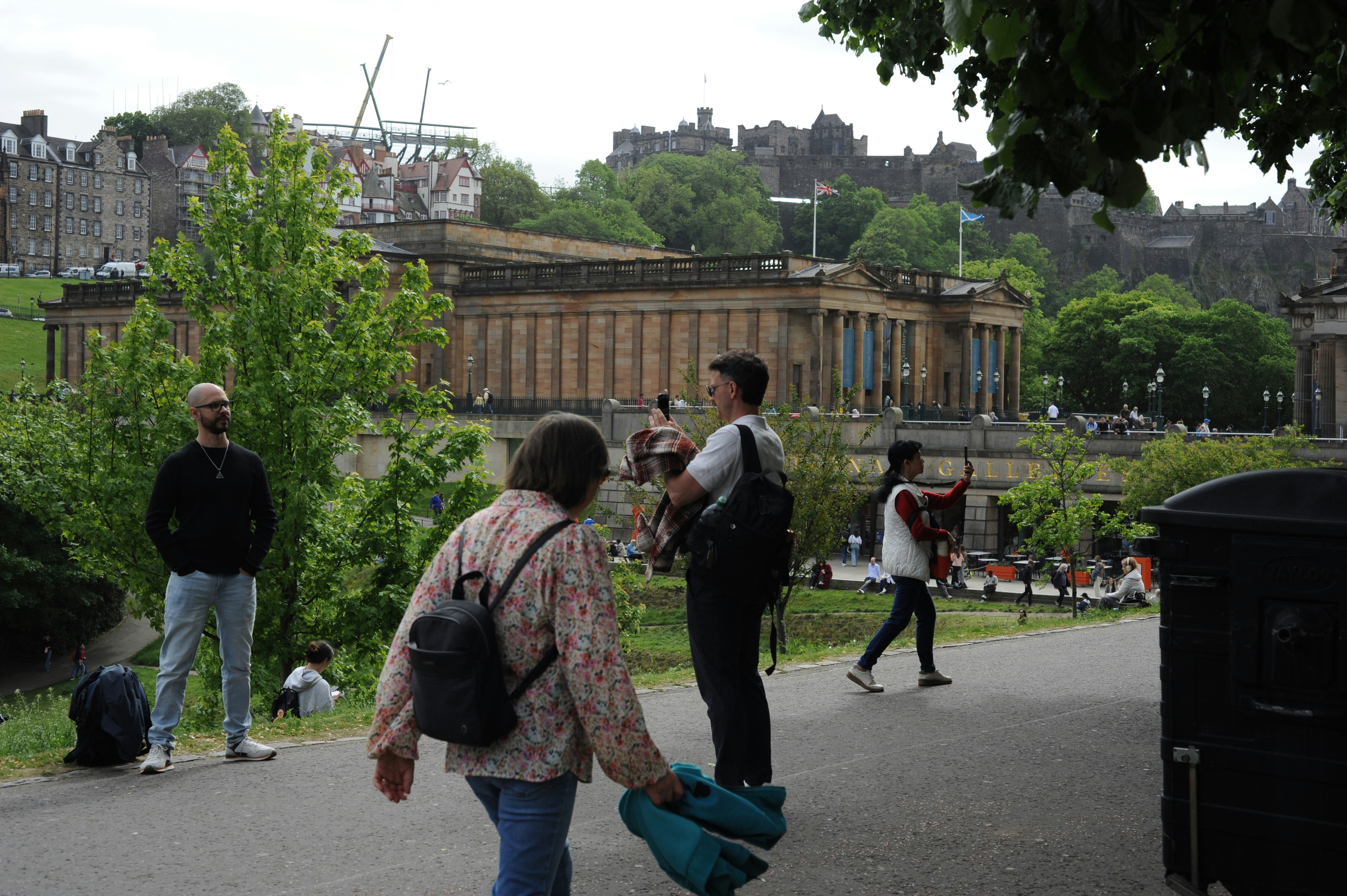 People walking in a park with historic buildings in edinburgh.