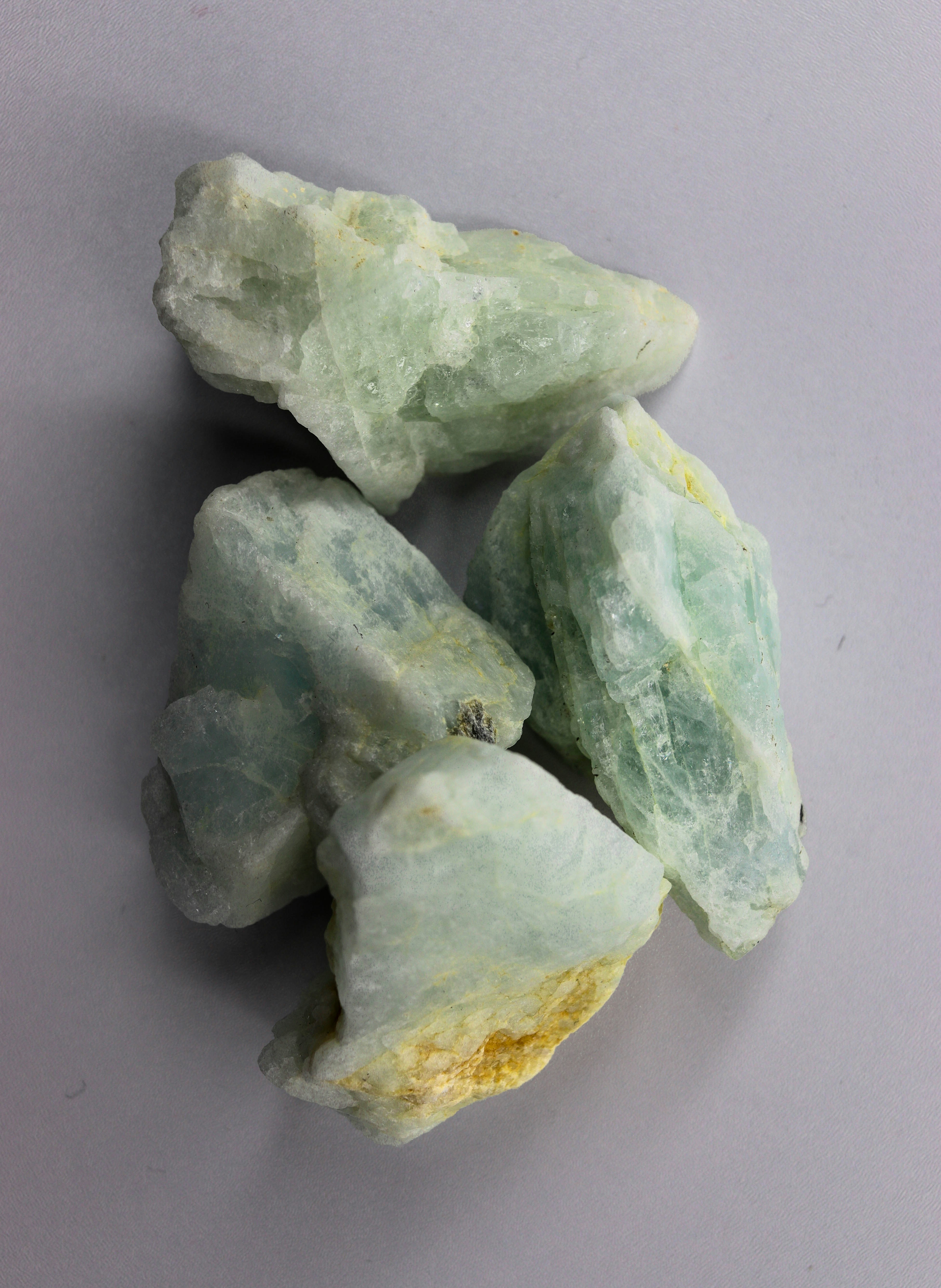 Several rough light green and white mineral stones.