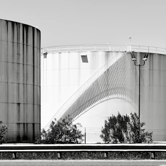 Two large industrial storage tanks with a spiral staircase.