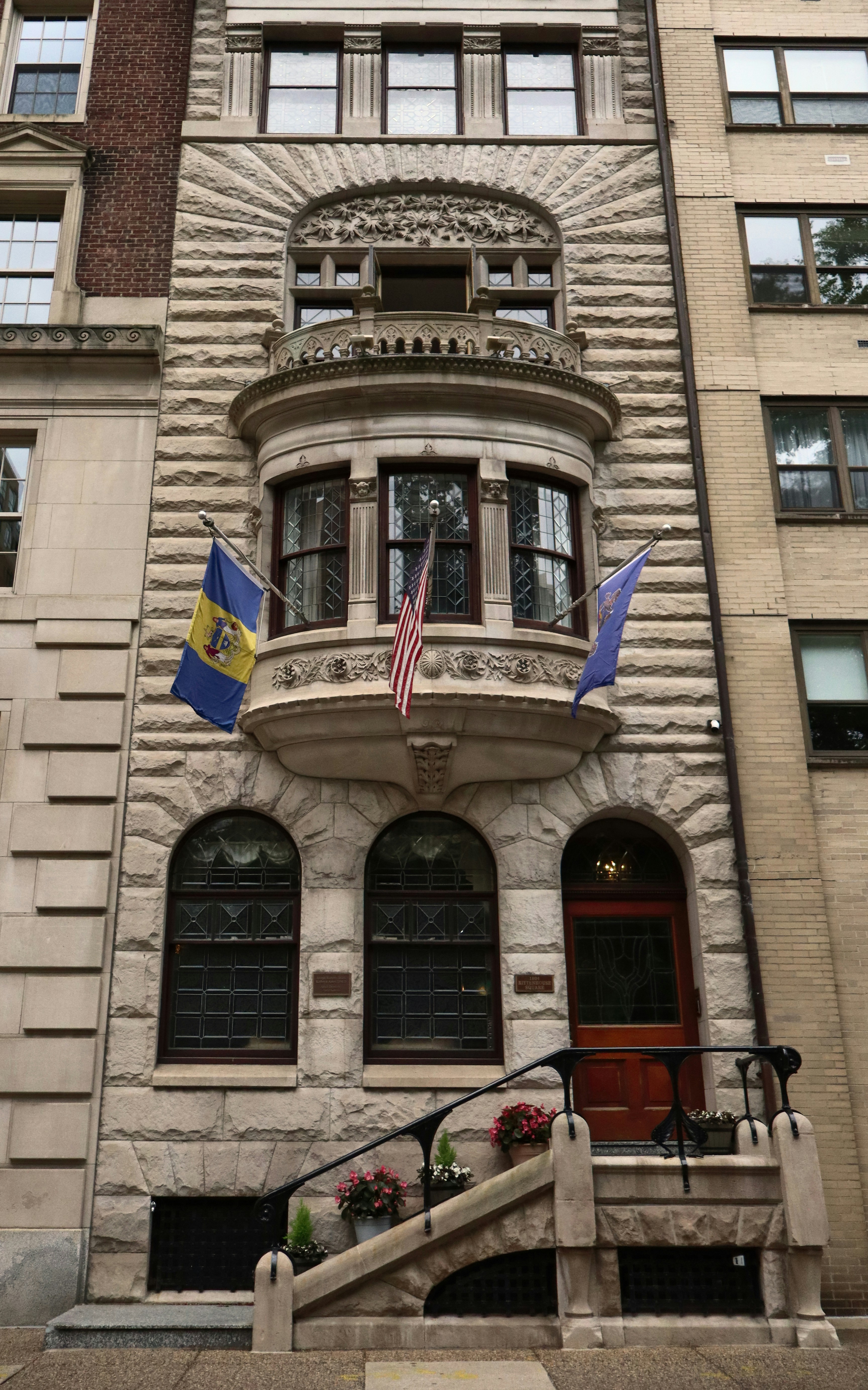 Ornate stone building with flags and a decorative bay window.