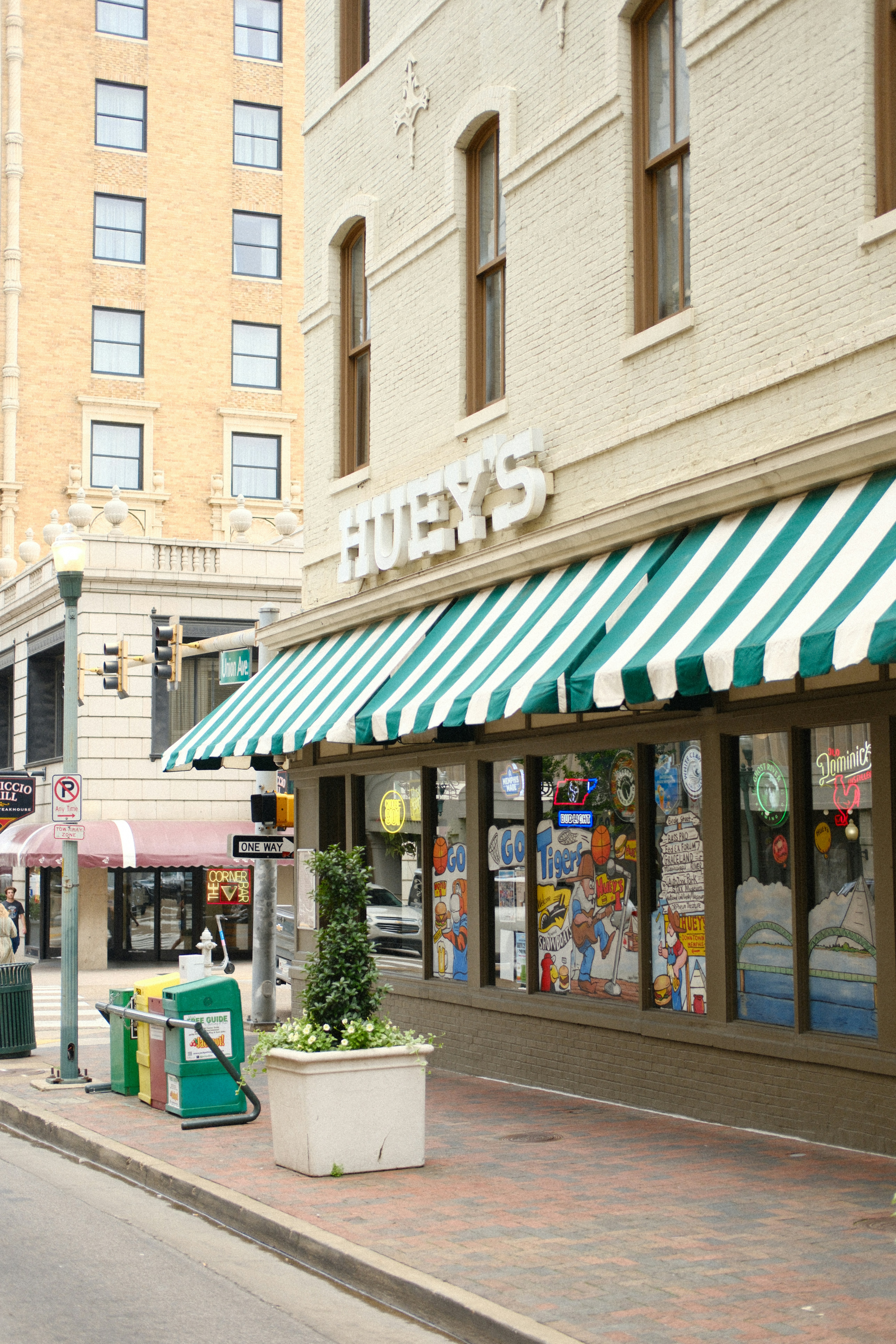 City street with huey's storefront and green striped awning.