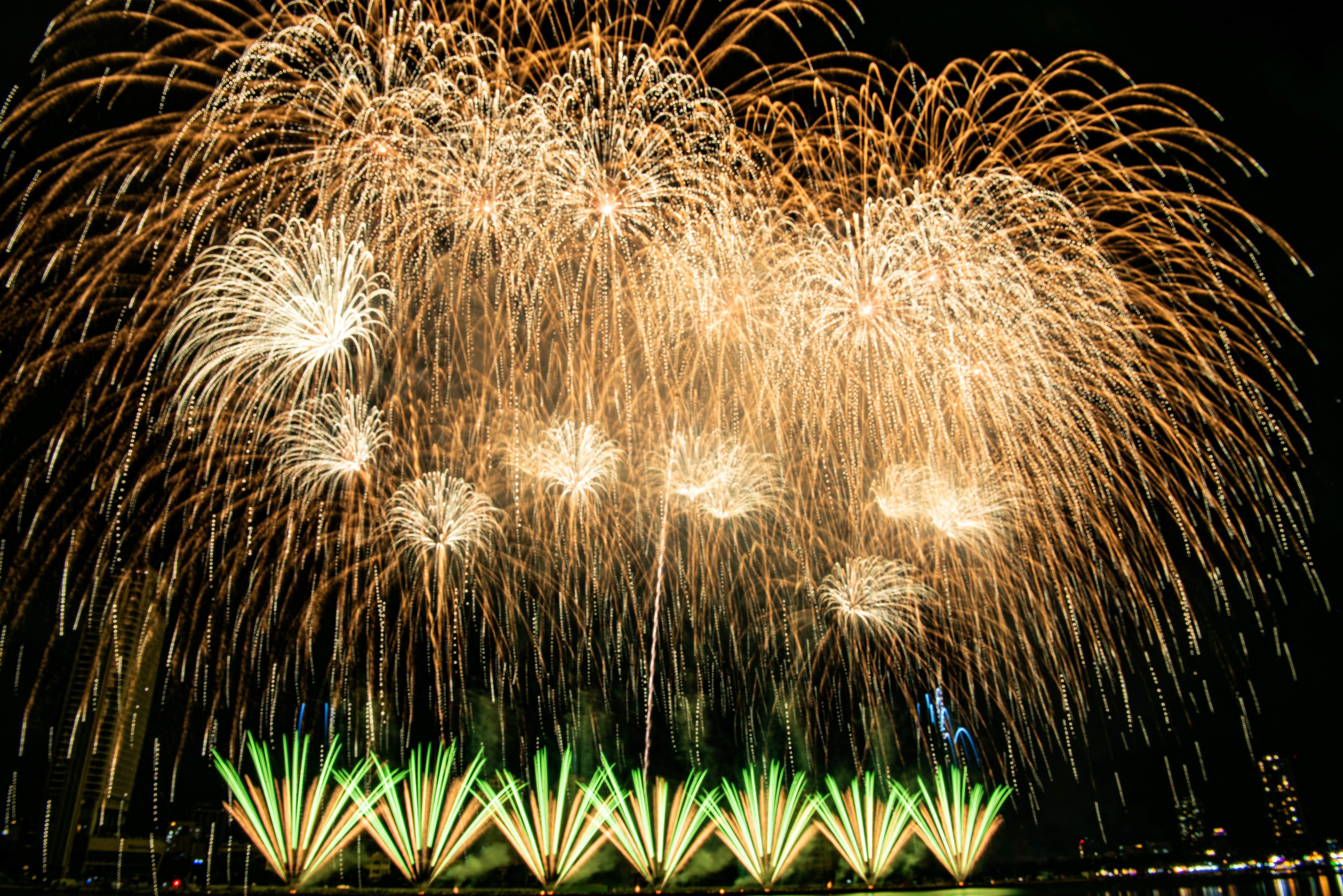 Stunning golden fireworks display with green light fountains.