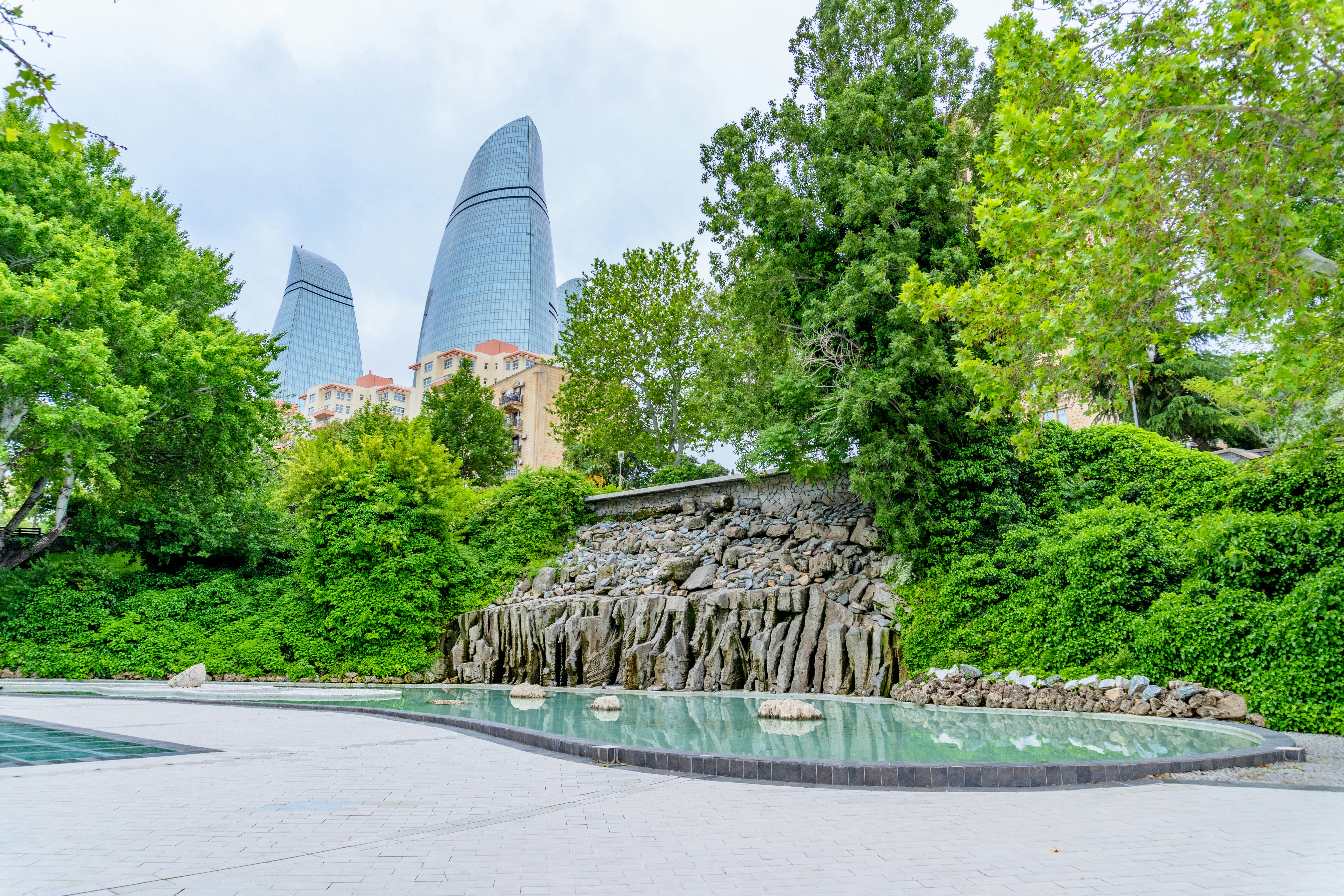 Flame towers, lush greenery, and a waterfall with reflective pool.