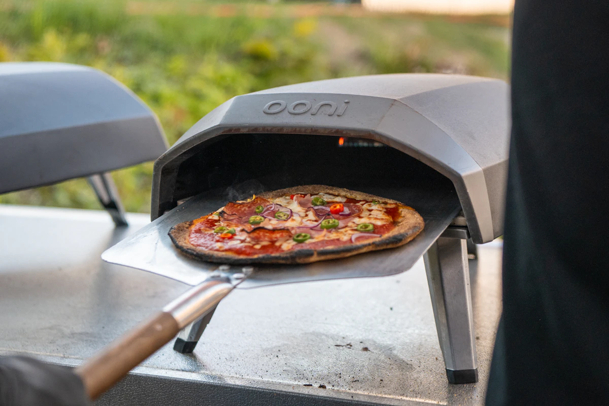 Fresh outdoor baked artisan pizza on wooden peel