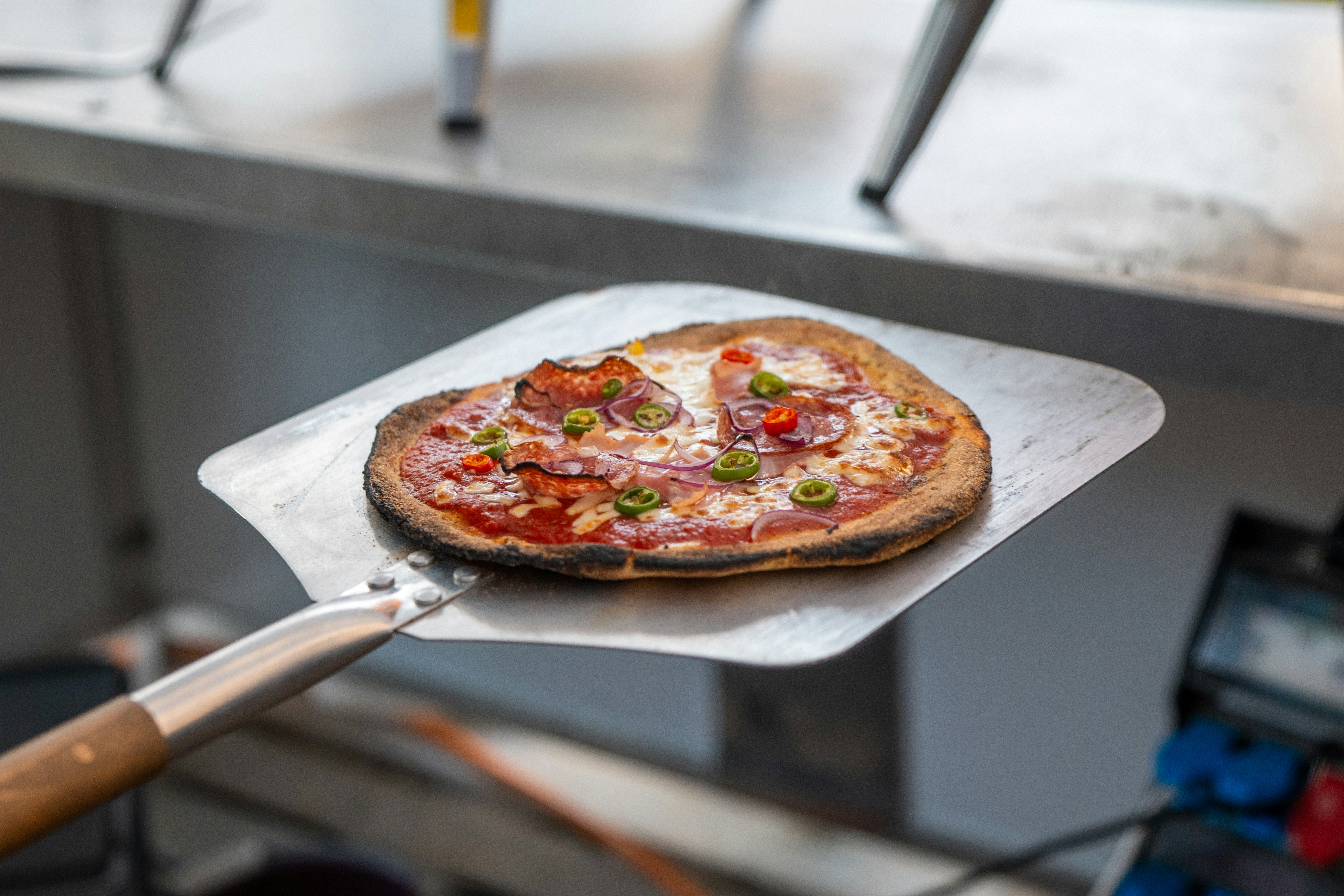 A small, freshly baked pizza on a metal pizza peel.