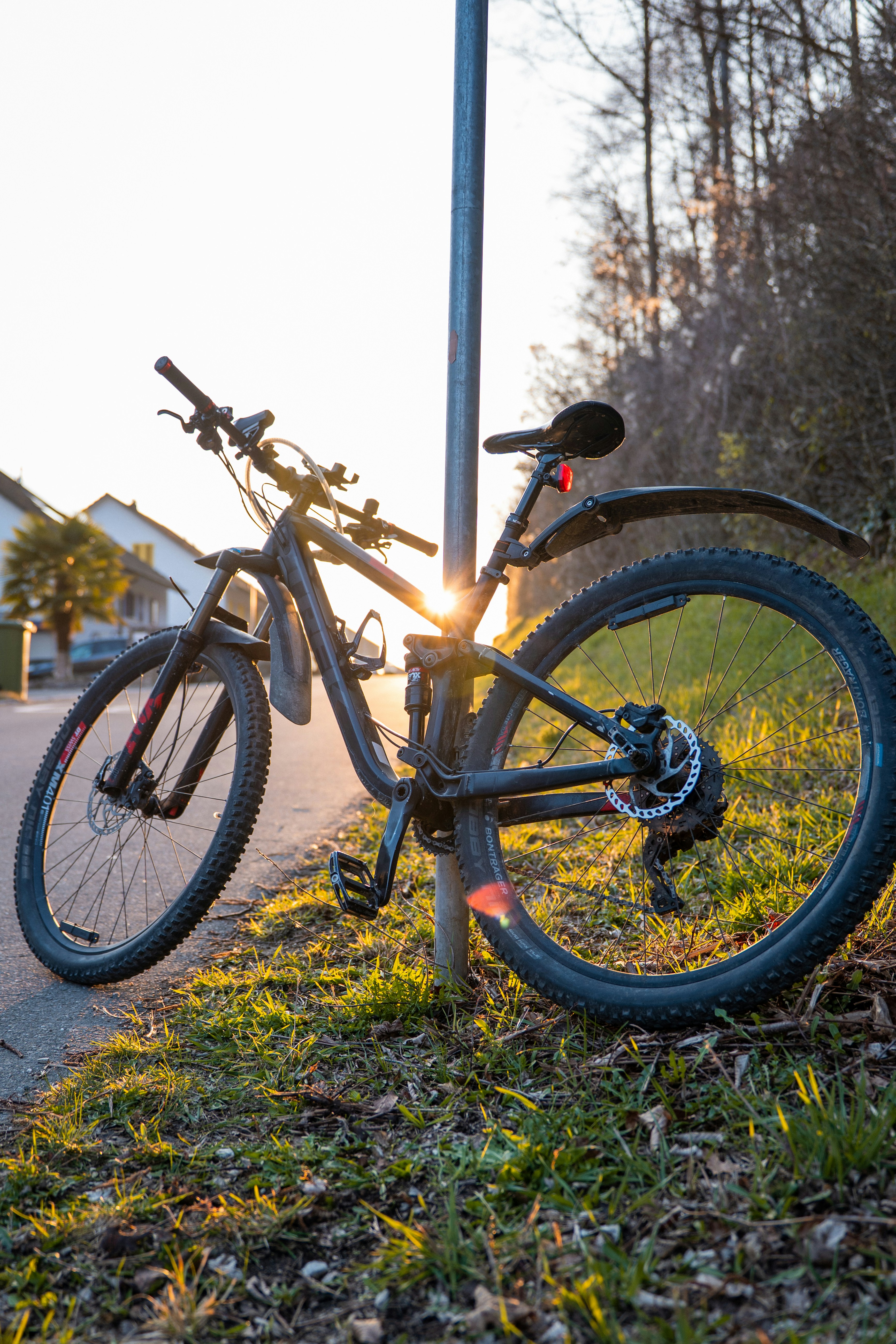 Black mountain bike leaning against a pole at sunset.