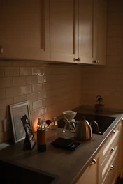 Kitchen counter with coffee brewing equipment and warm ambient lighting.