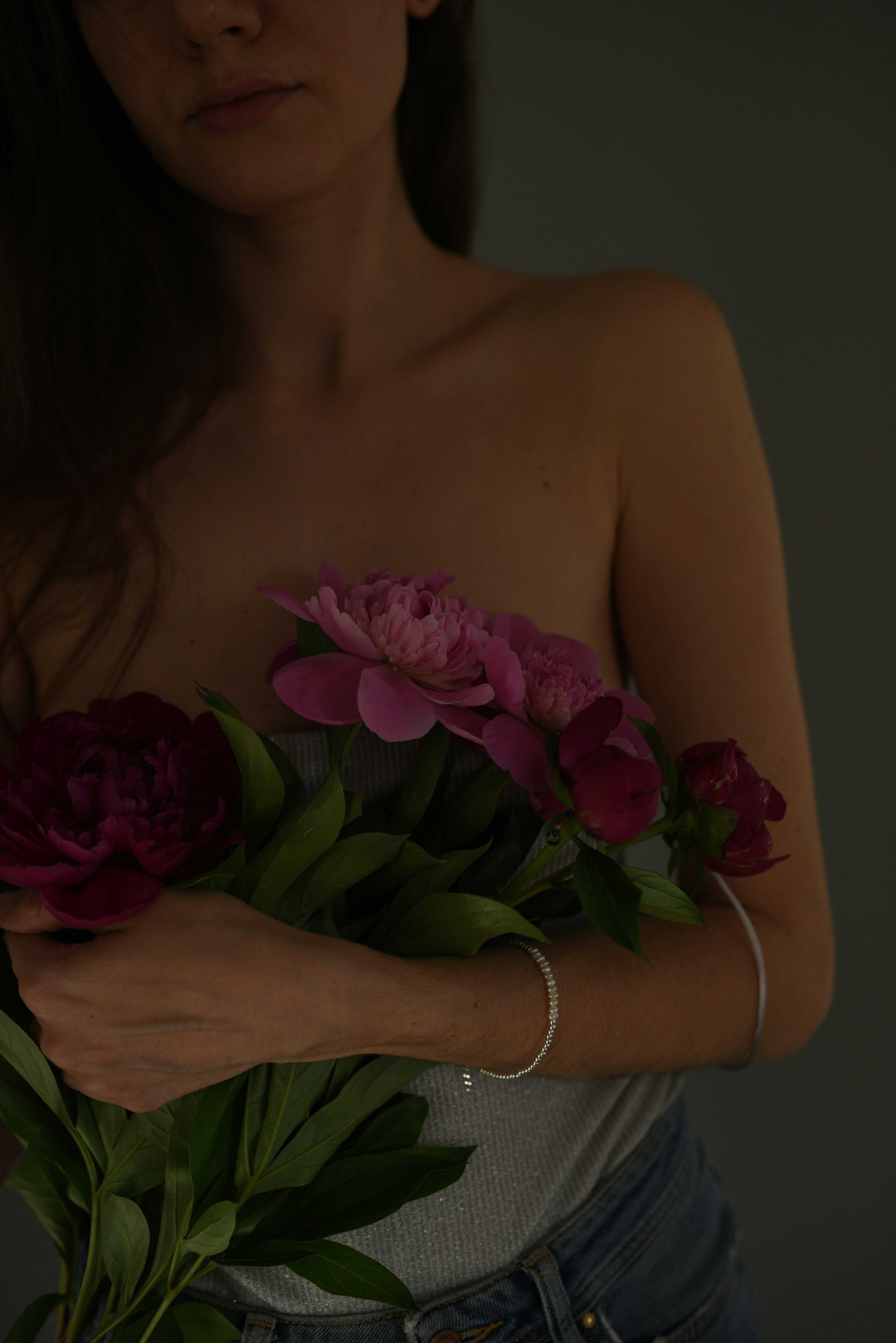 Woman holding vibrant pink and red peonies.