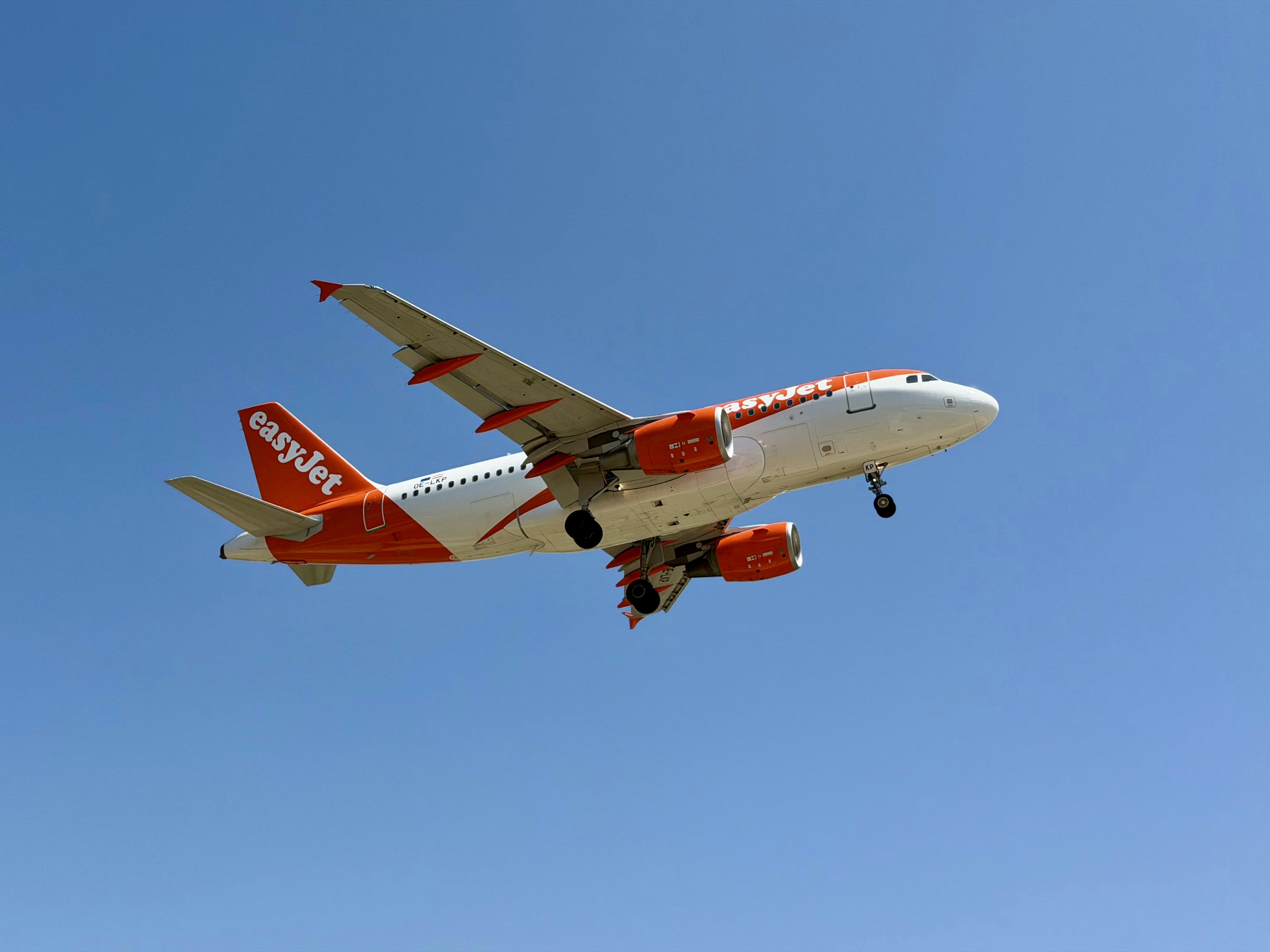 An easyjet airplane with landing gear down in blue sky.