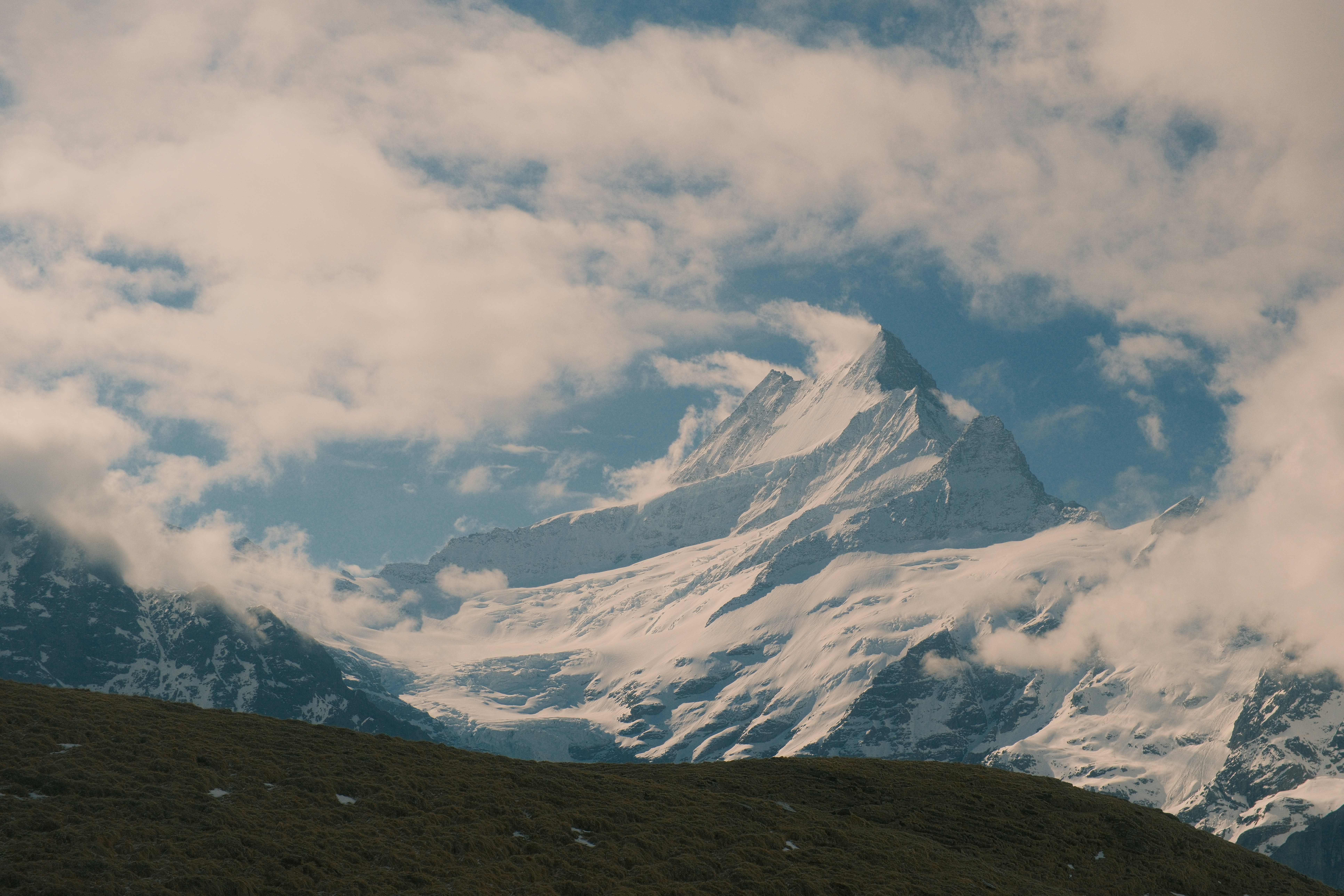 Schneebedeckter Berggipfel, teilweise von Wolken verdeckt.