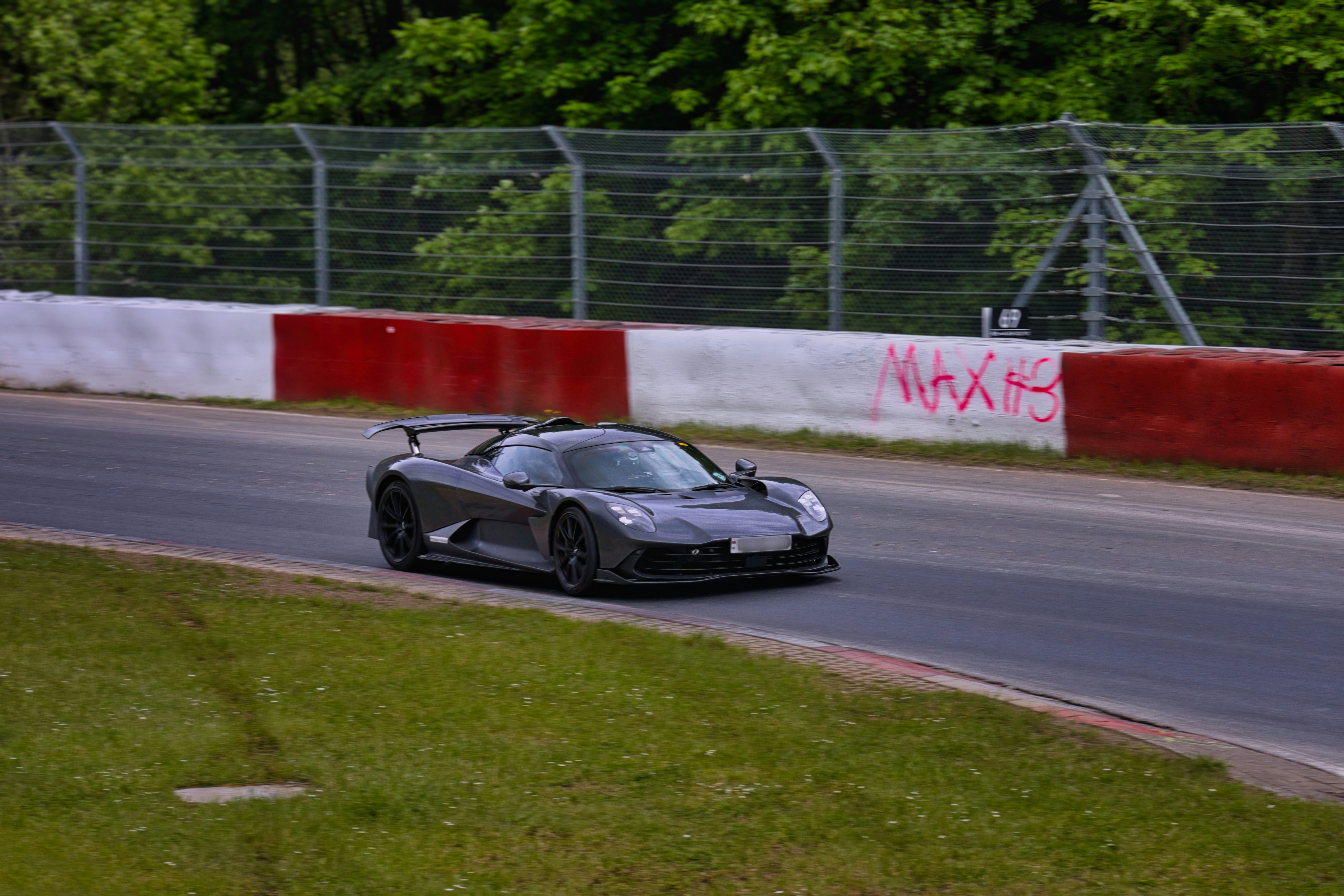 Dark grey sports car speeding on a race track.
