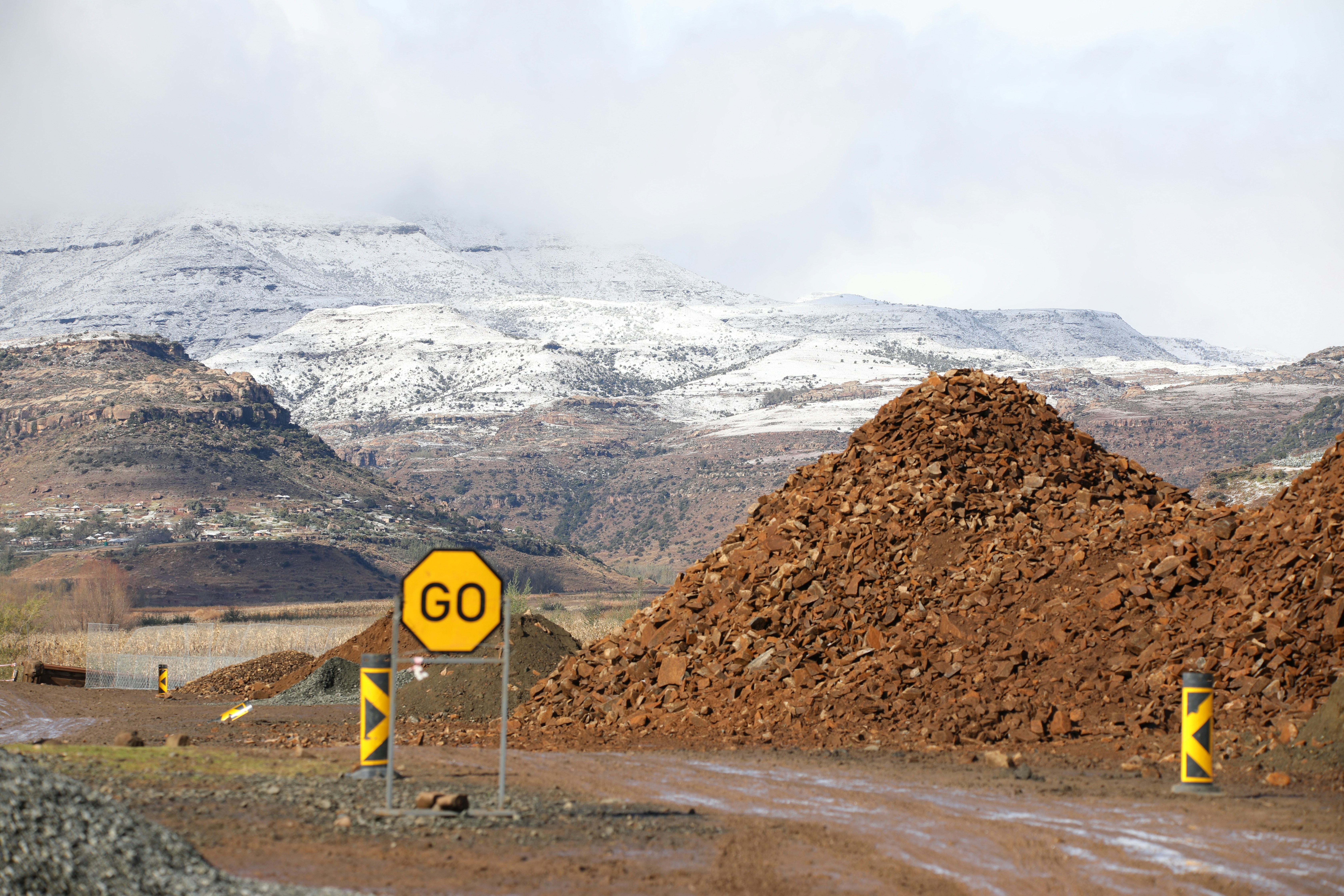 A "go" sign on a dirt road with snowy mountains.