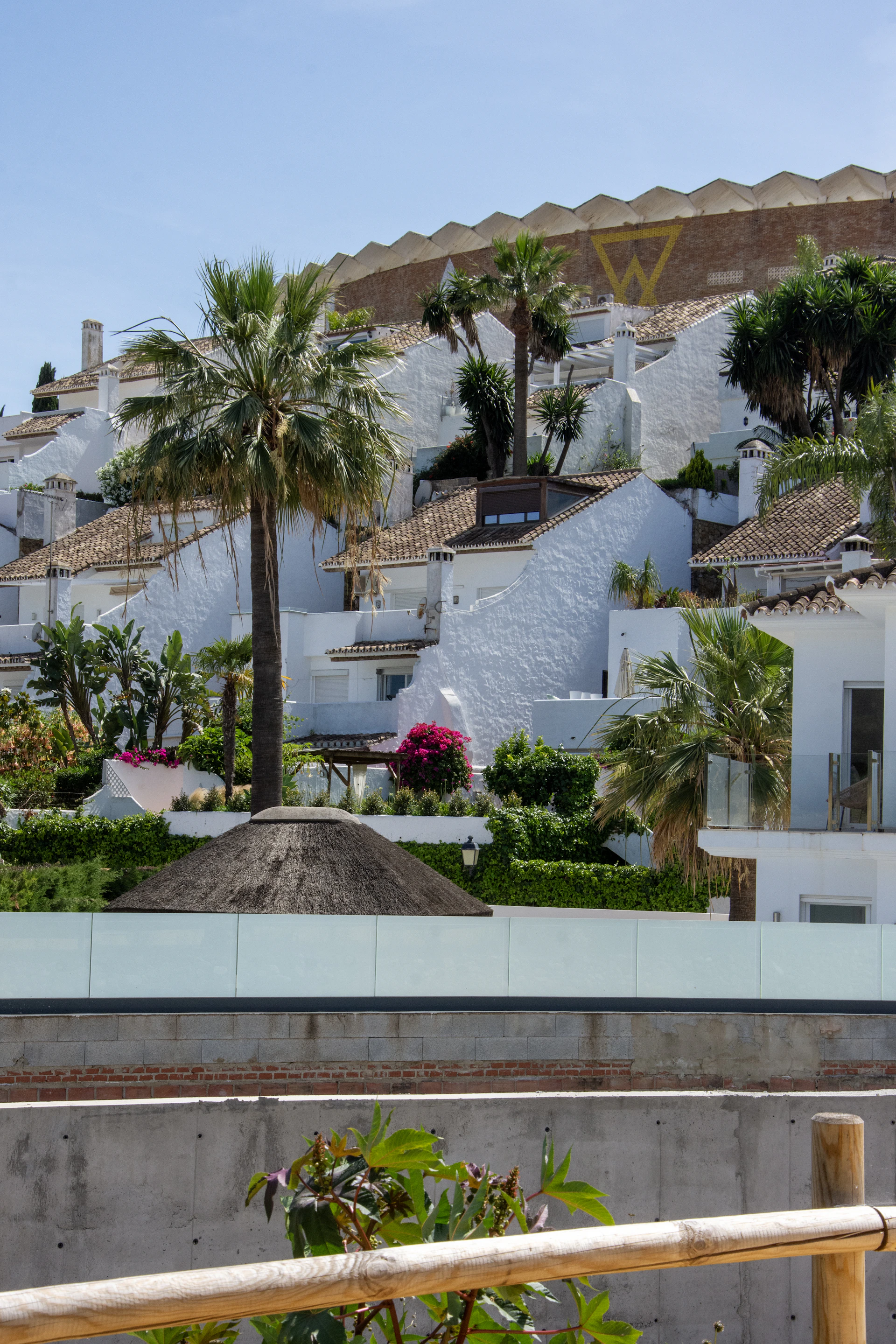 Whitewashed hillside village with lush gardens and palm trees.