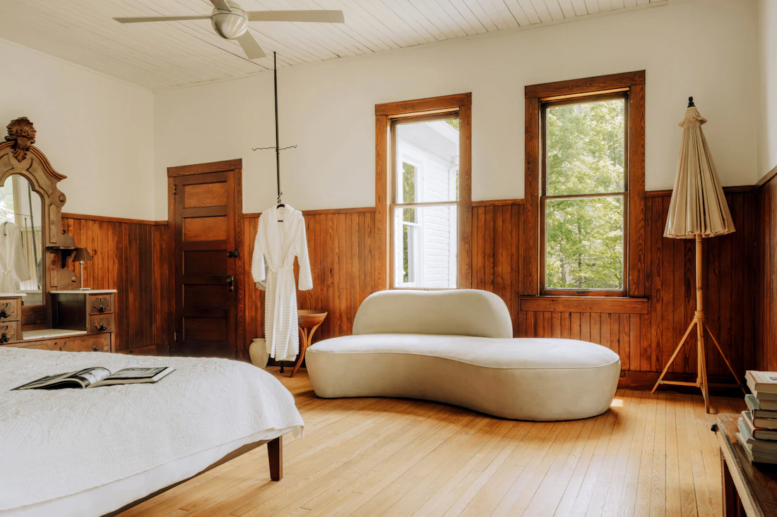 A bright room with wooden walls, a bed and a sofa