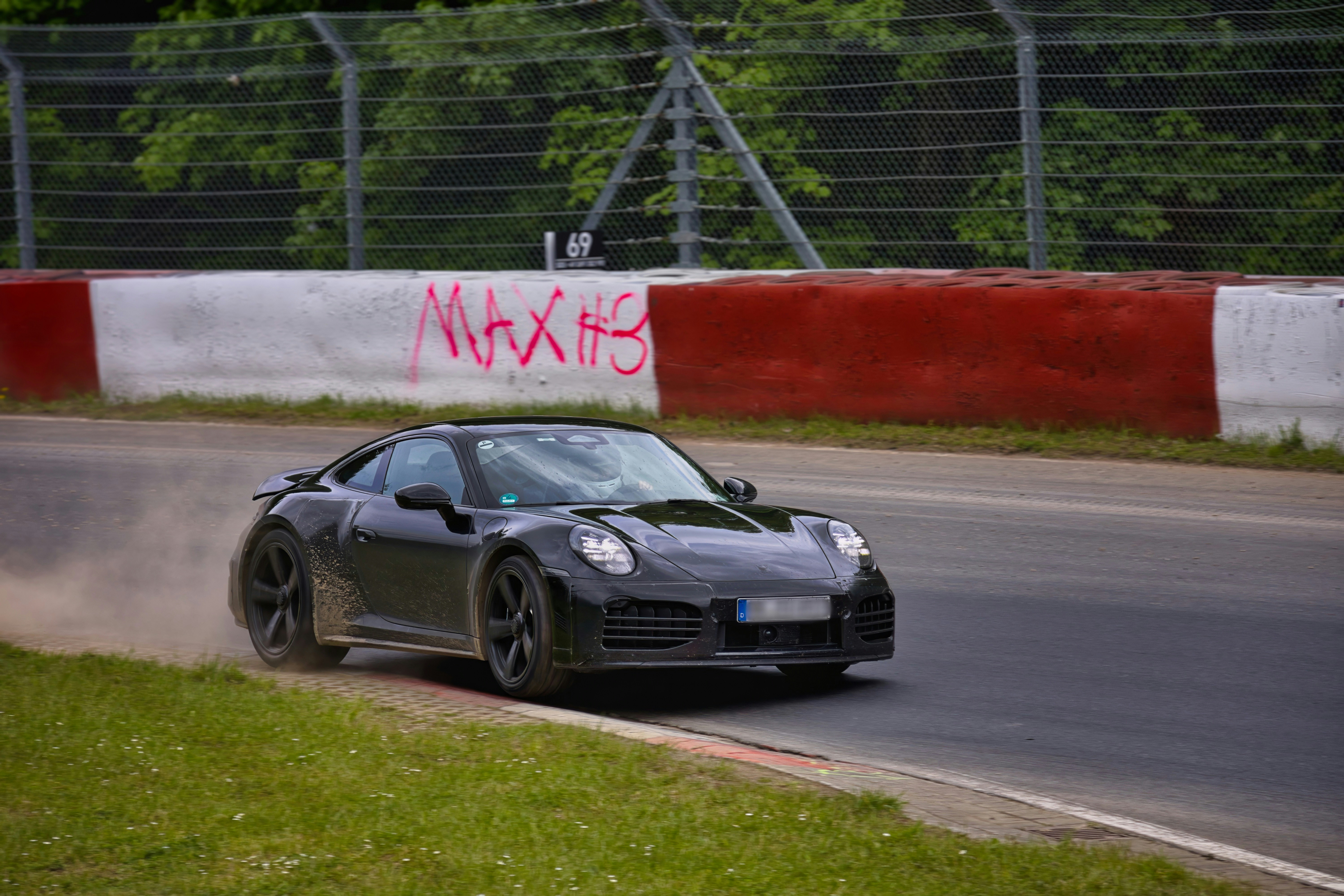 Black porsche sports car on a race track with dust.