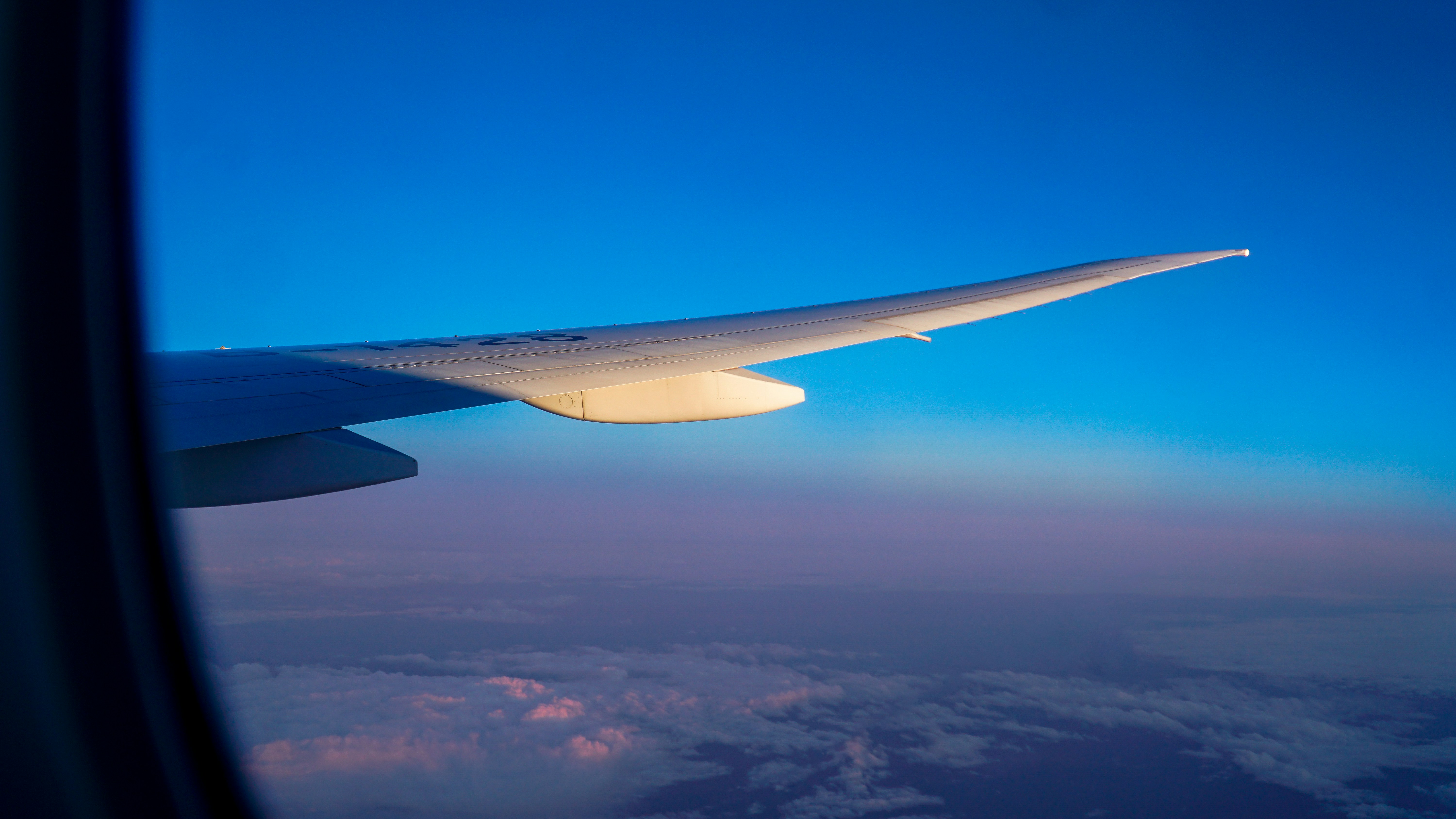Airplane wing soaring above clouds during sunrise.