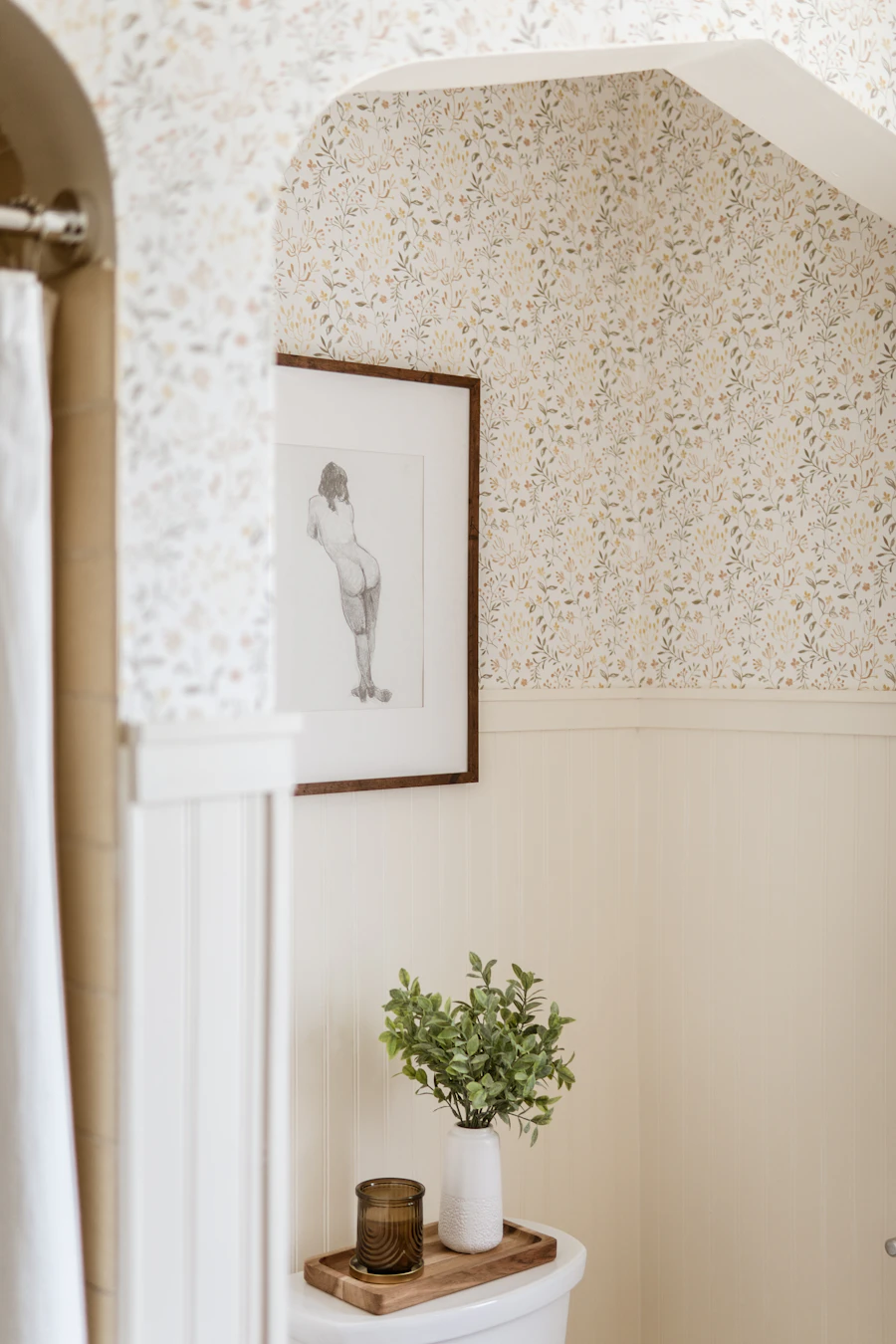 Bathroom corner with framed figure artwork and botanical wallpaper