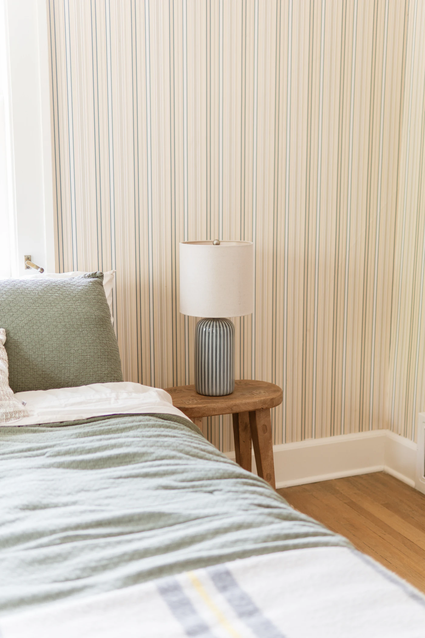 Schlafzimmer mit grüner Bettwäsche und gestreifter Nachttischlampe