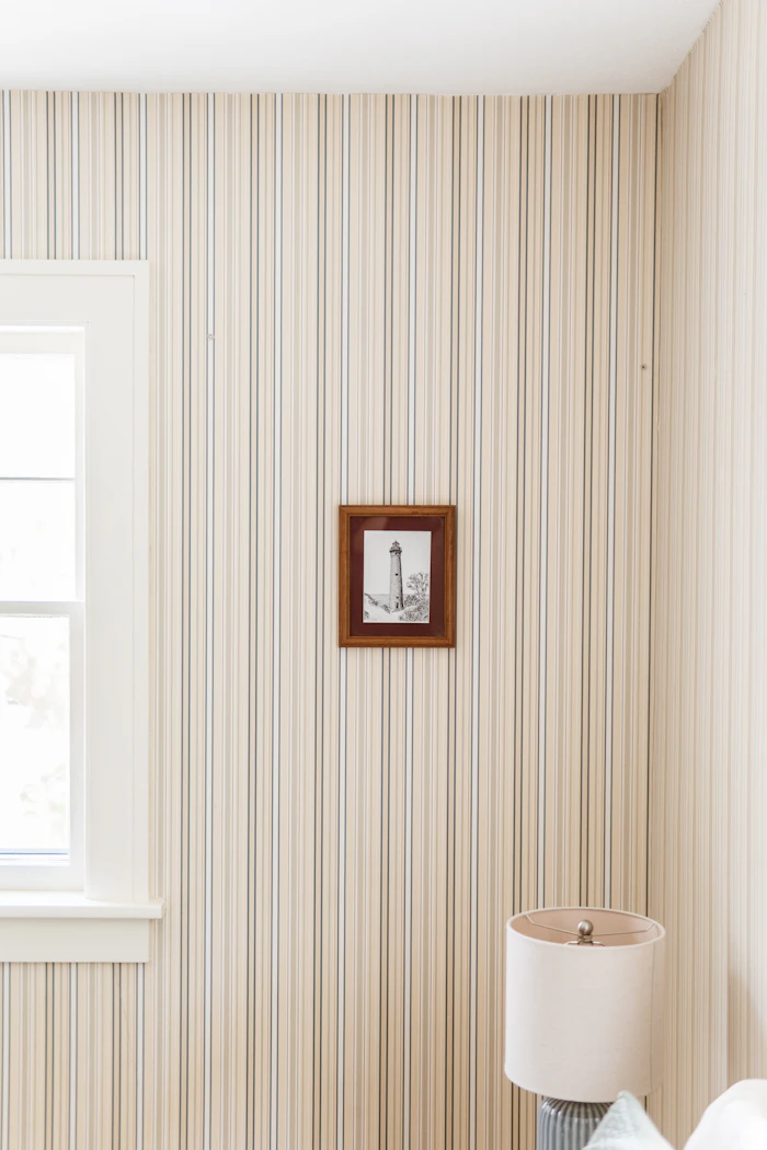Striped wallpaper with a framed lighthouse picture and a window