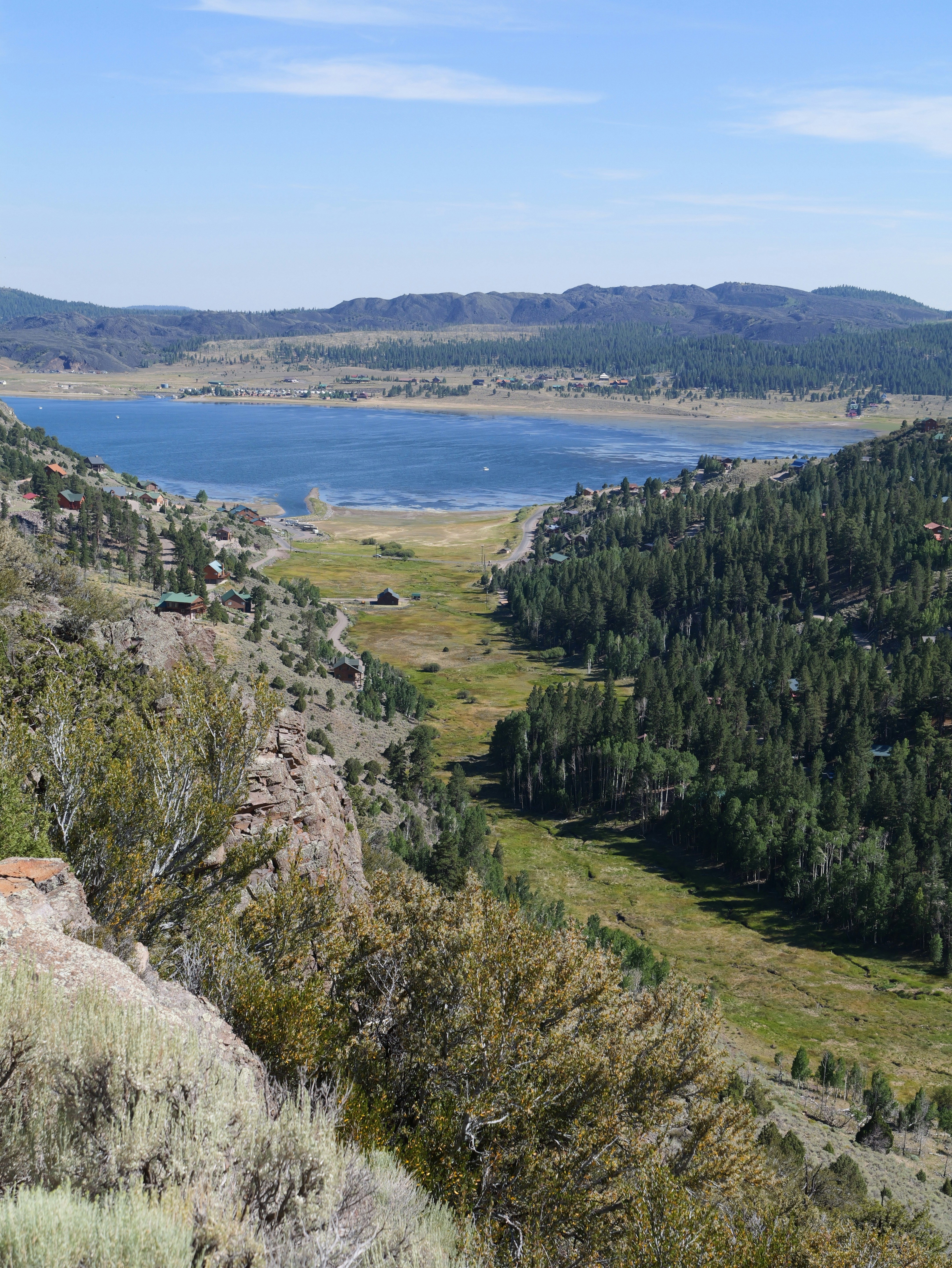 Mountain valley with a lake and dense pine forests.