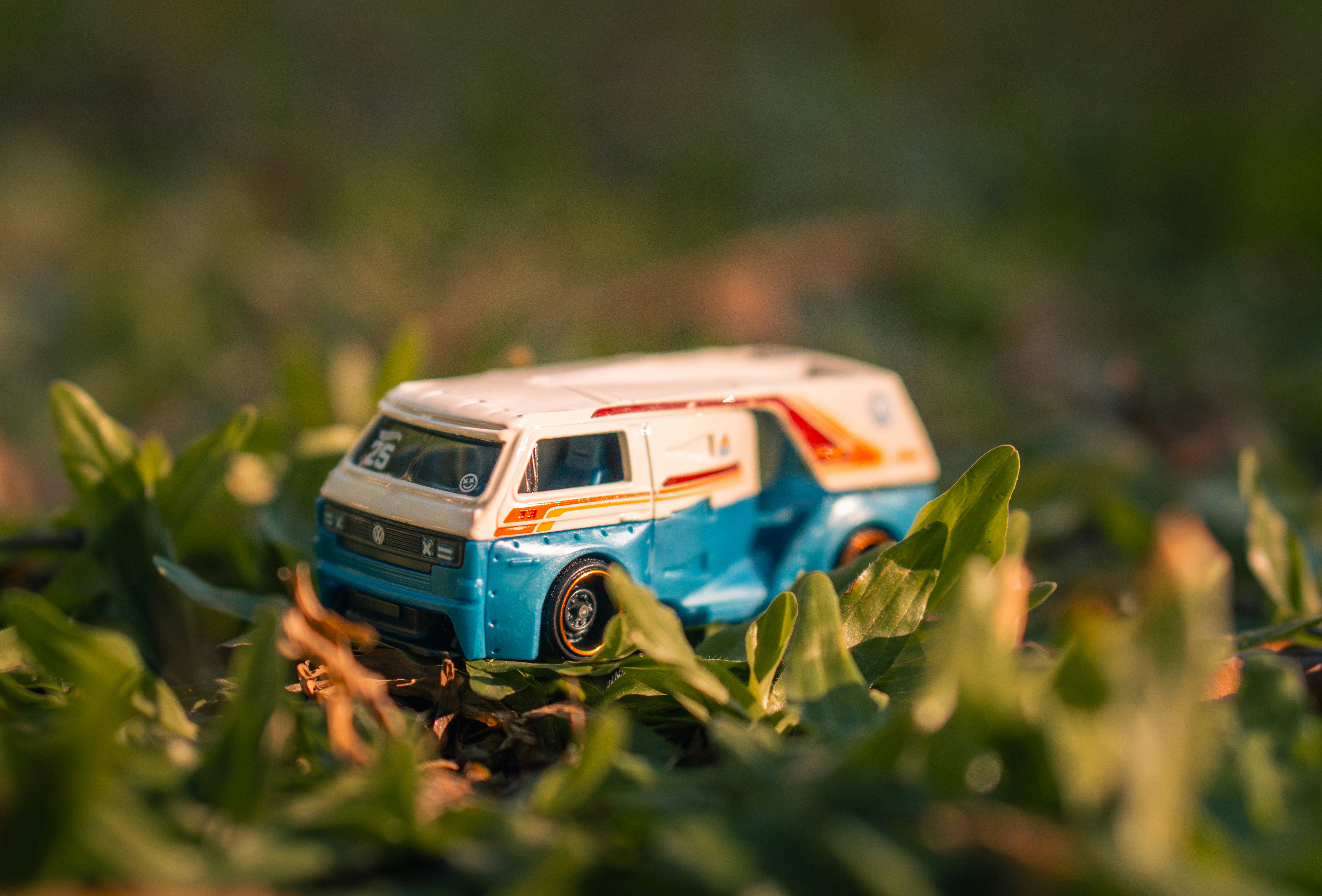 Miniature blue and white toy van resting in green grass.